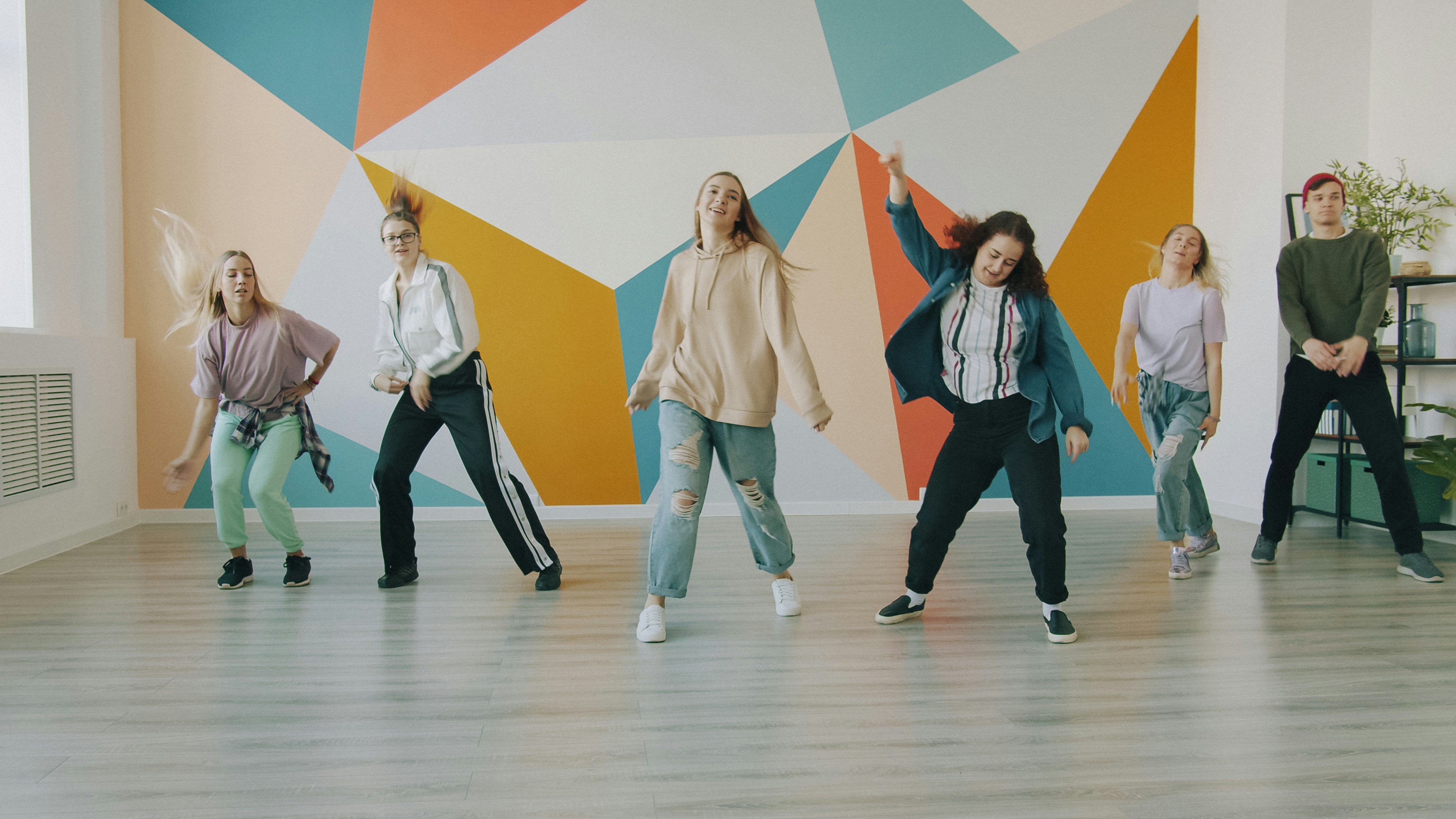 Group of creative young people female and male are dancing in modern studio jumping gesturing having fun. Culture, lifestyle and hobby concept.