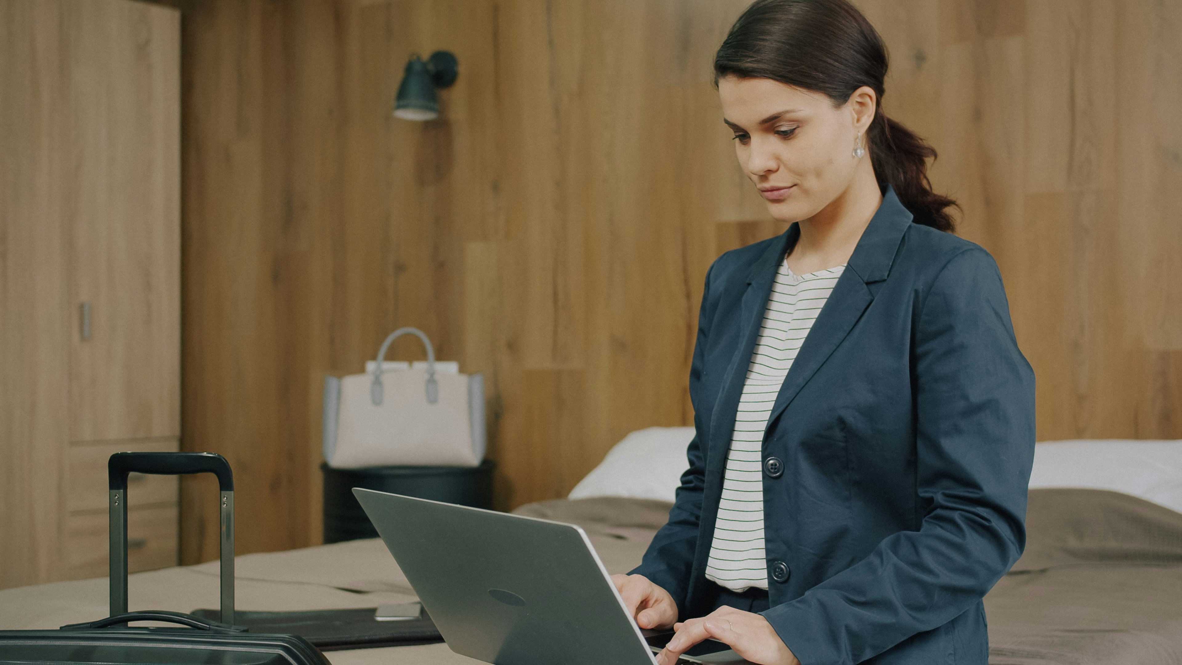 A woman in a blazer using a laptop in a hotel room
