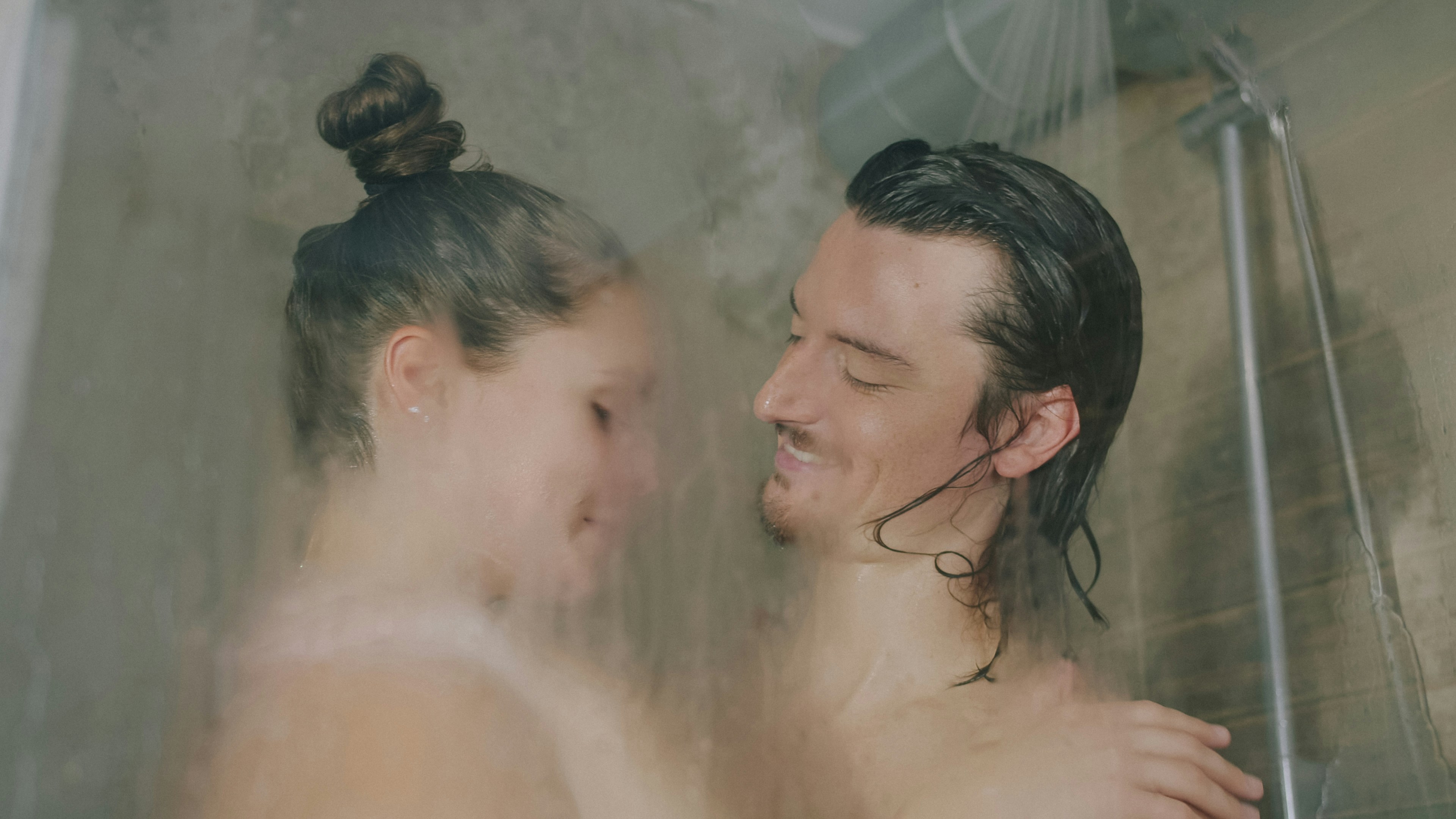 A man and a woman smiling at each other in a steamy shower
