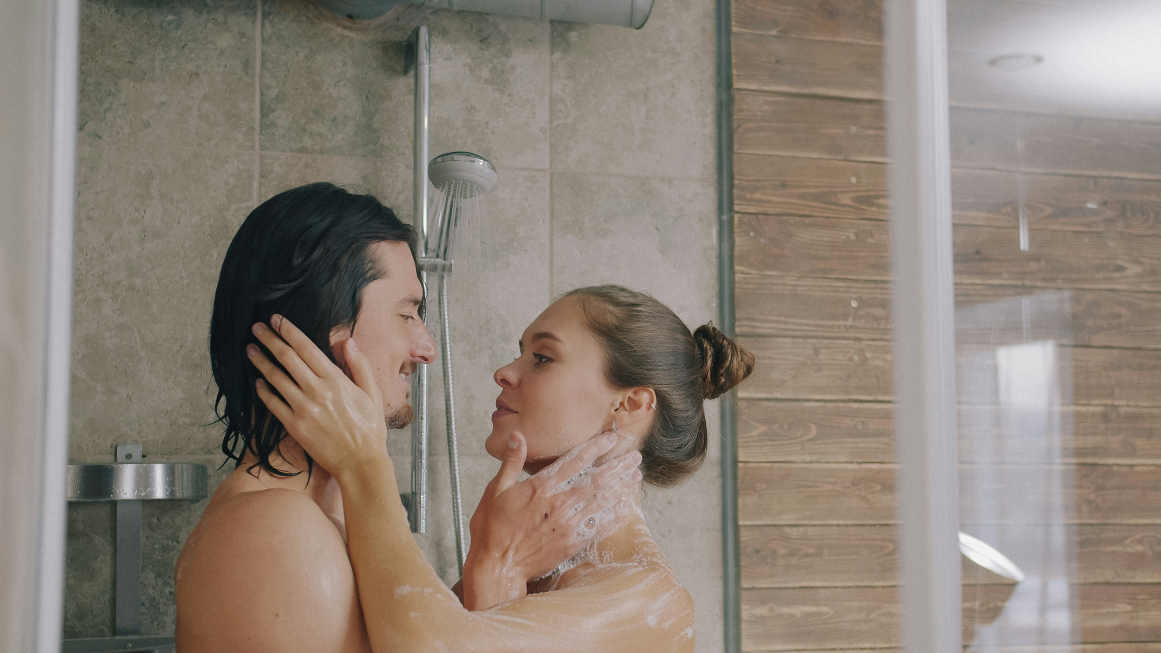 A man and a woman in a shower with tiled walls