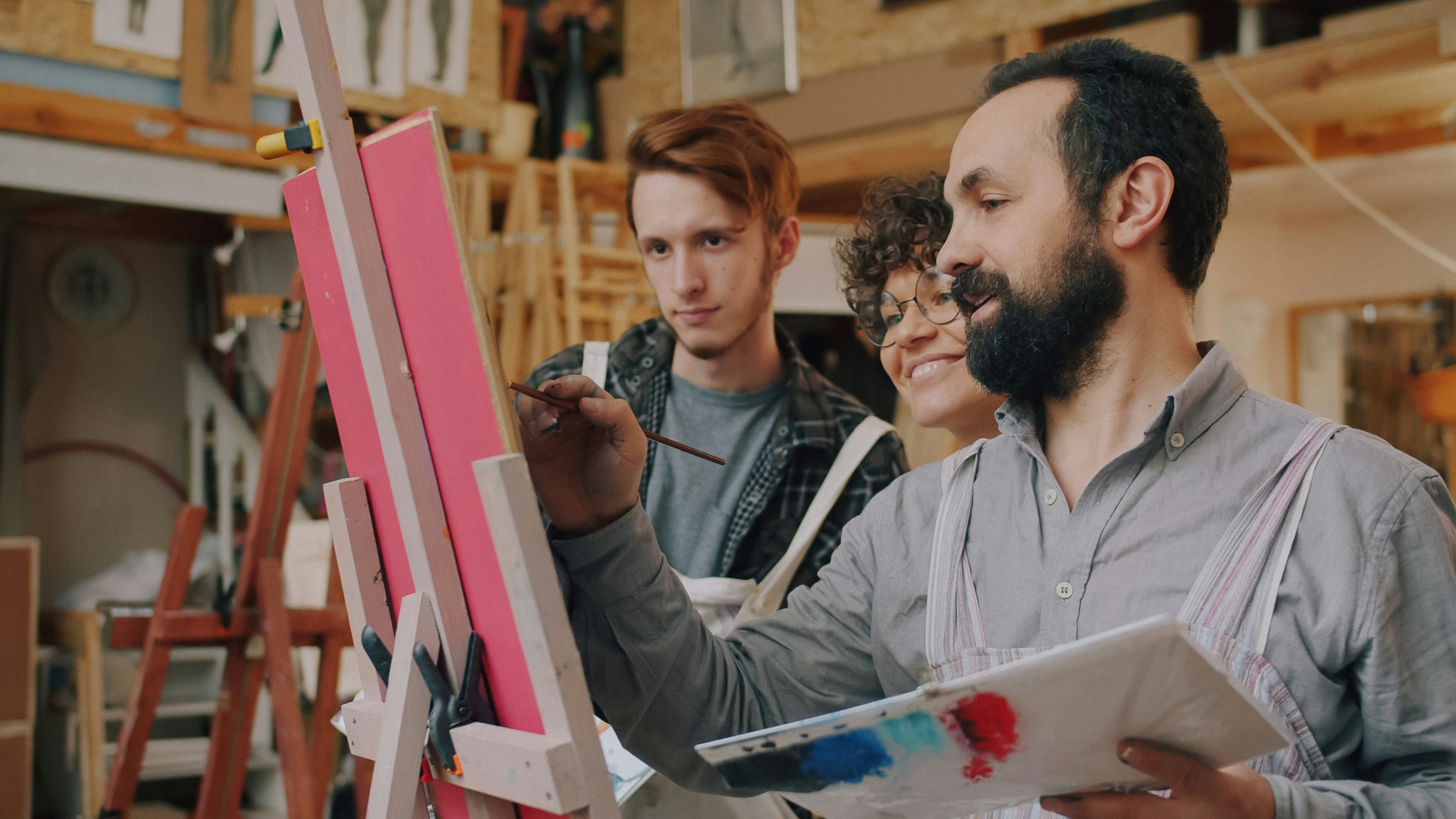 Artists collaborating around a canvas in a bright studio