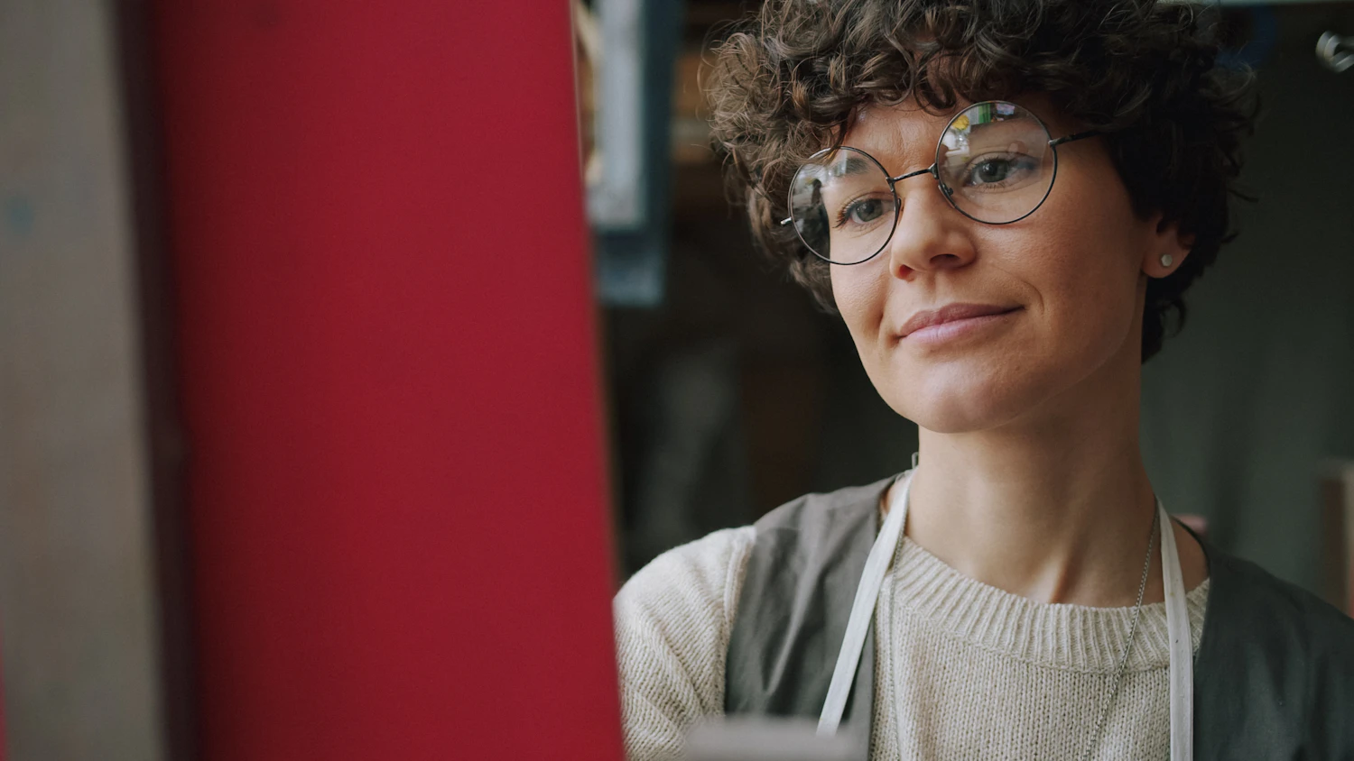 Lieve Donckers in an apron and round glasses, looking past the camera in her studio