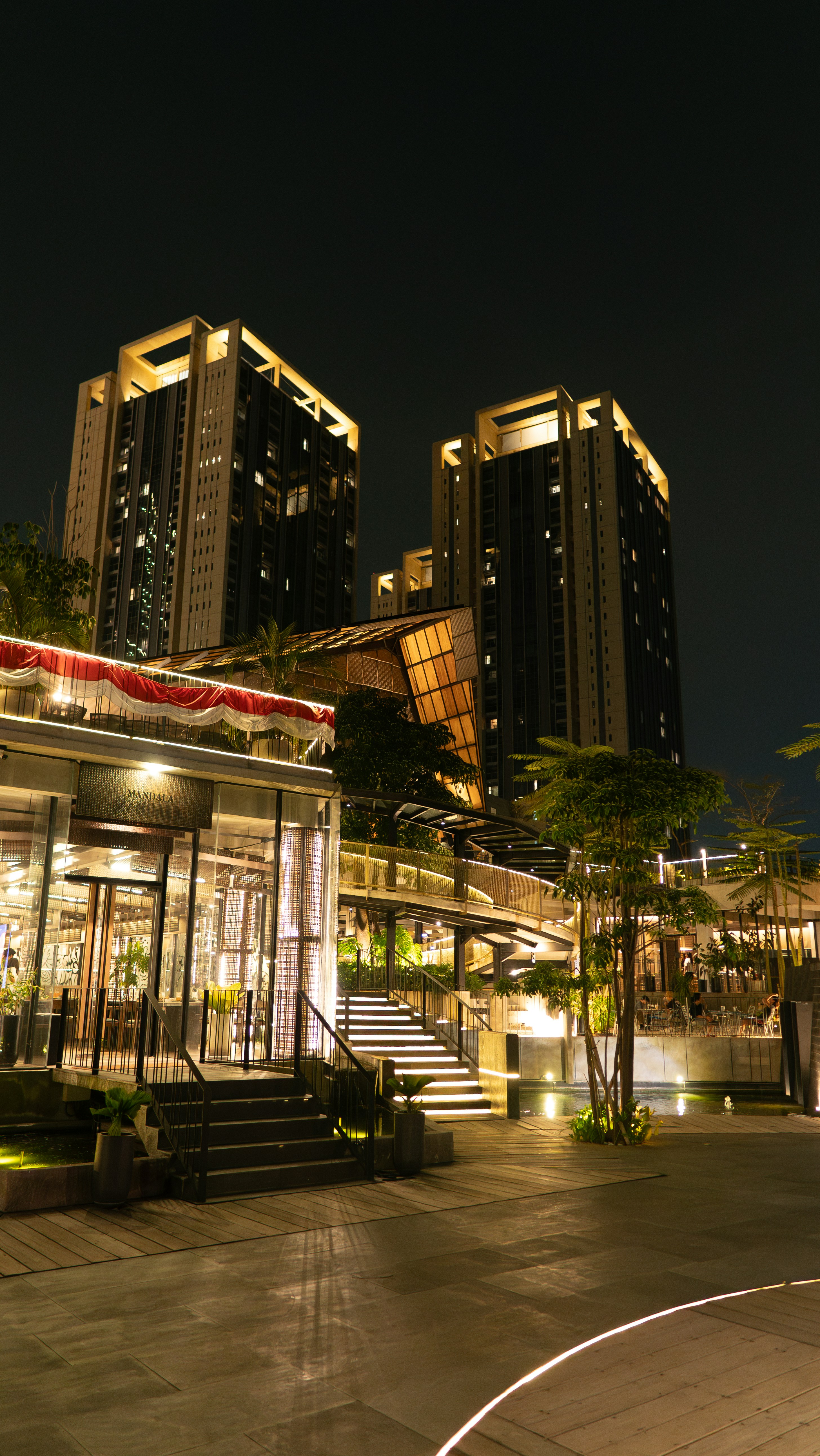 Moderne Hochhäuser hinter einem beleuchteten Restaurant mit Treppen bei Nacht