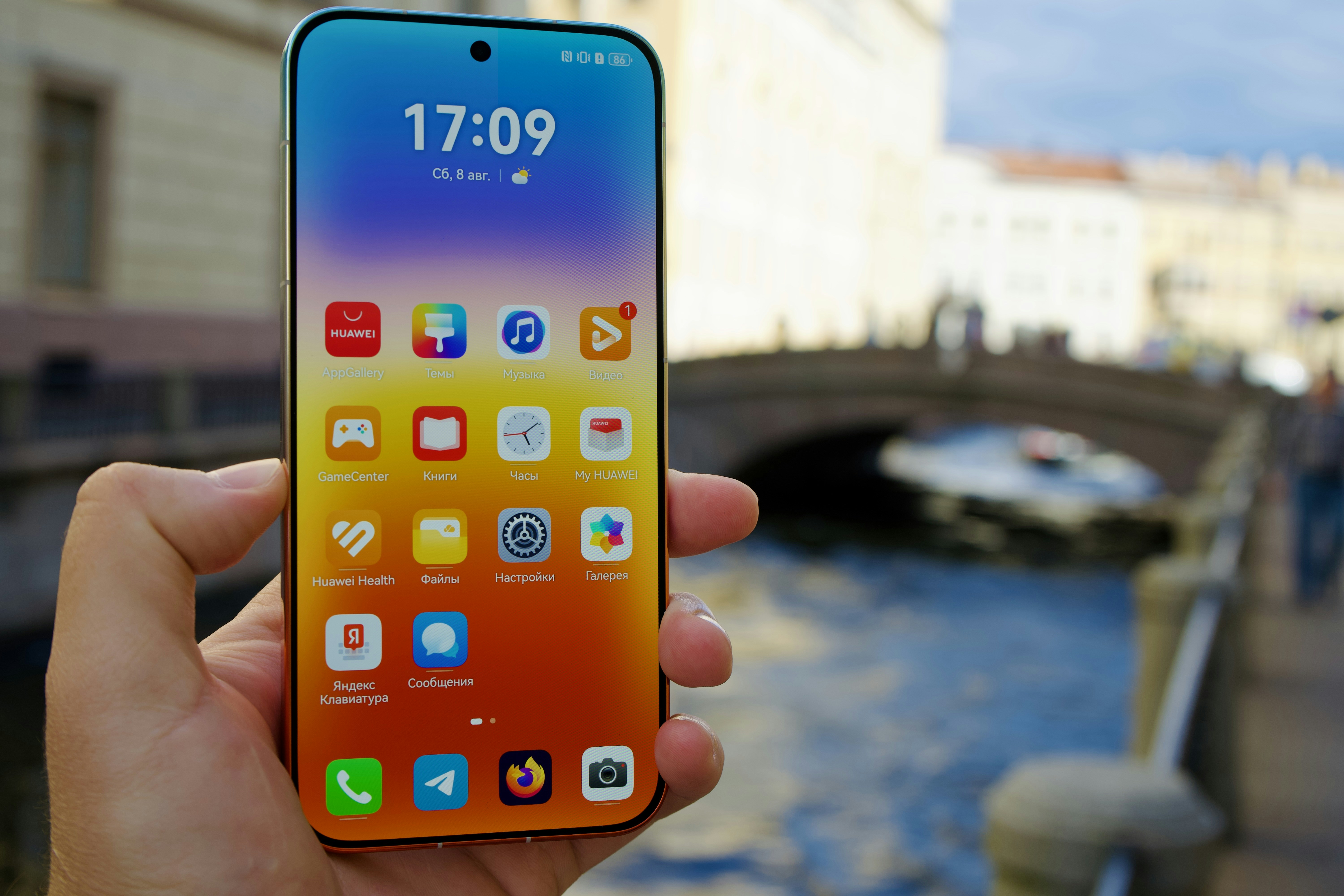A hand holding a smartphone with a colorful app interface against a blurred canal
