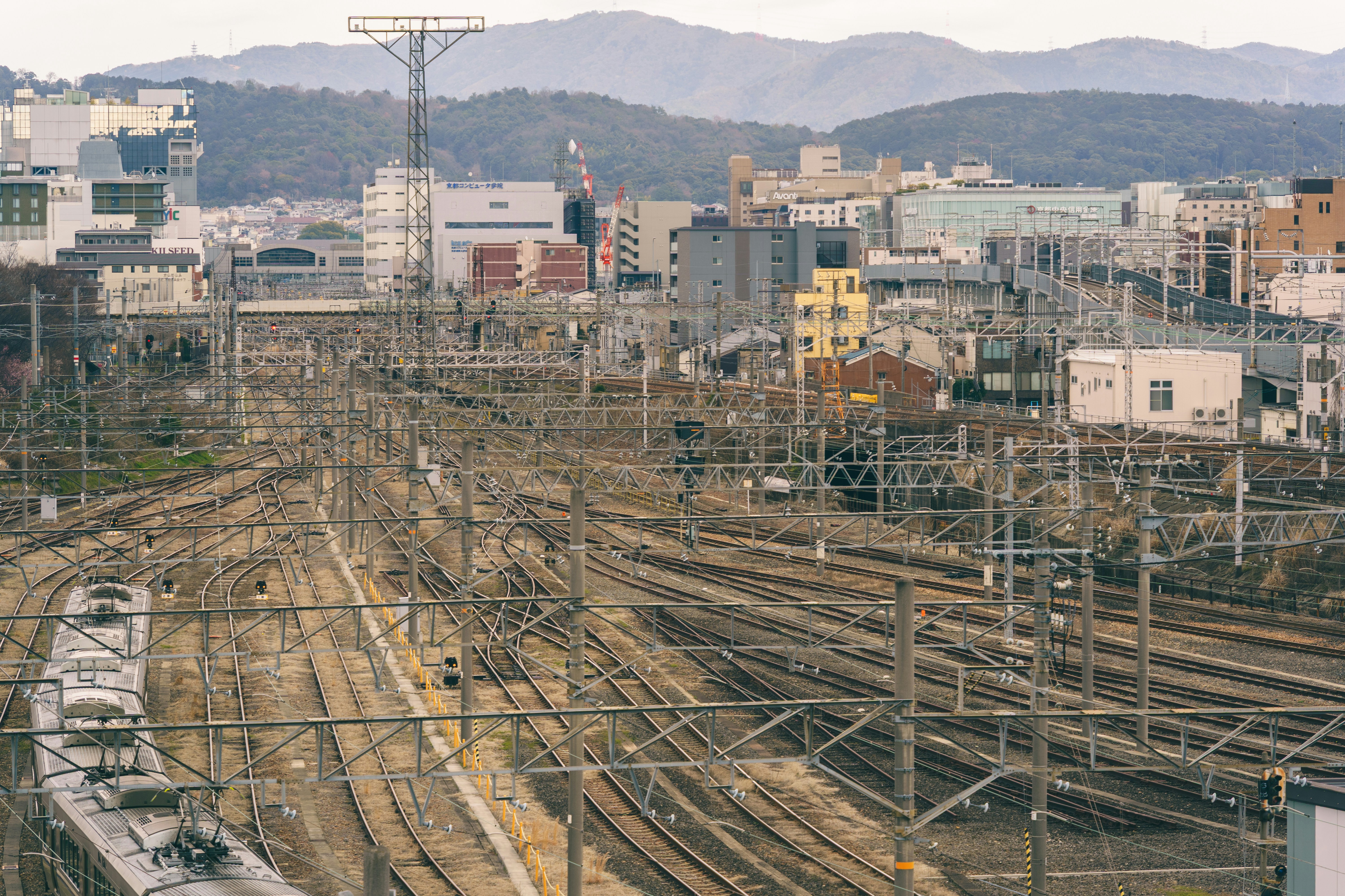 A complex network of railway tracks and overhead wires in Kyoto, Japan