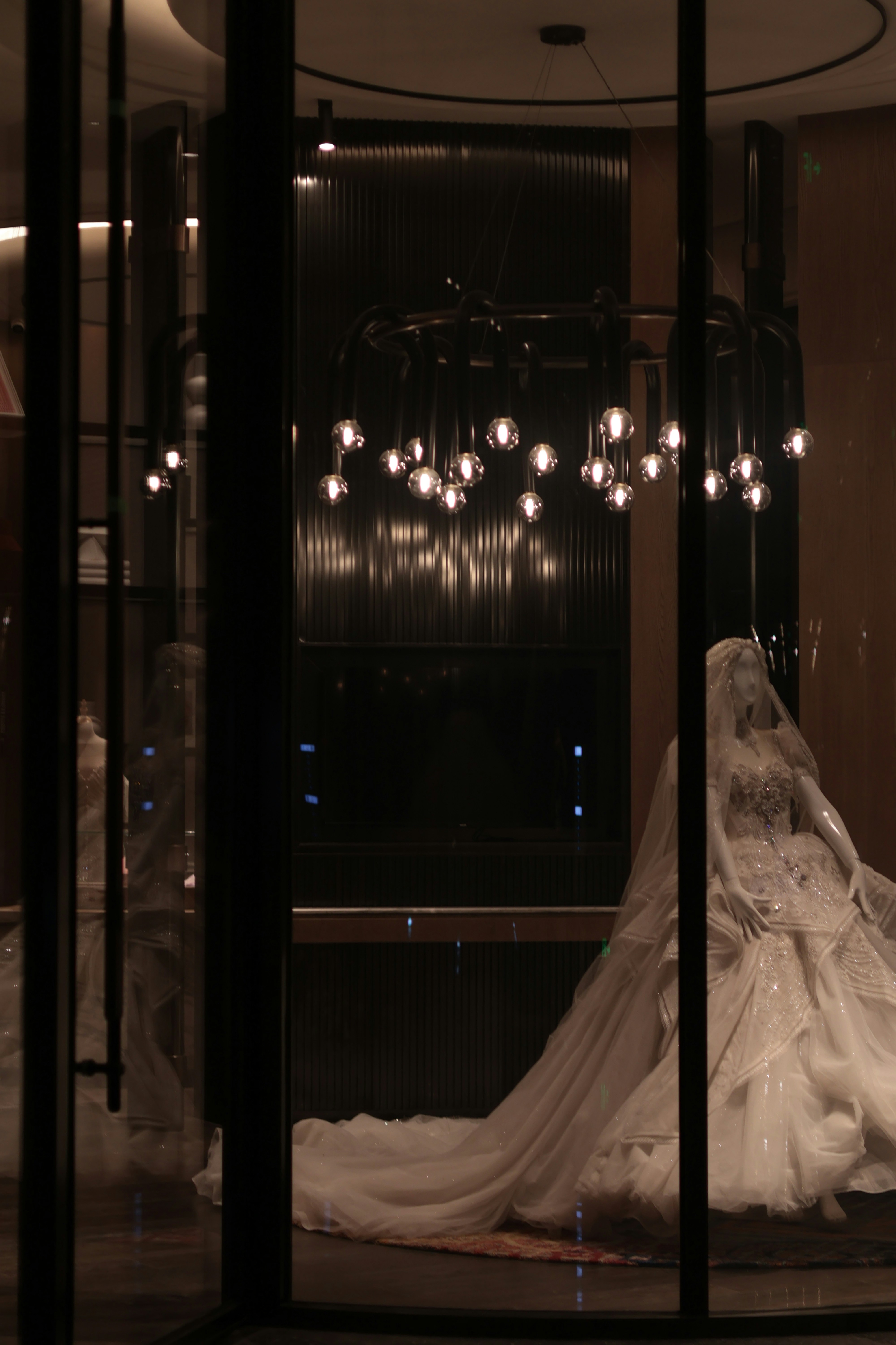 A white wedding dress on a mannequin in a dark shop window