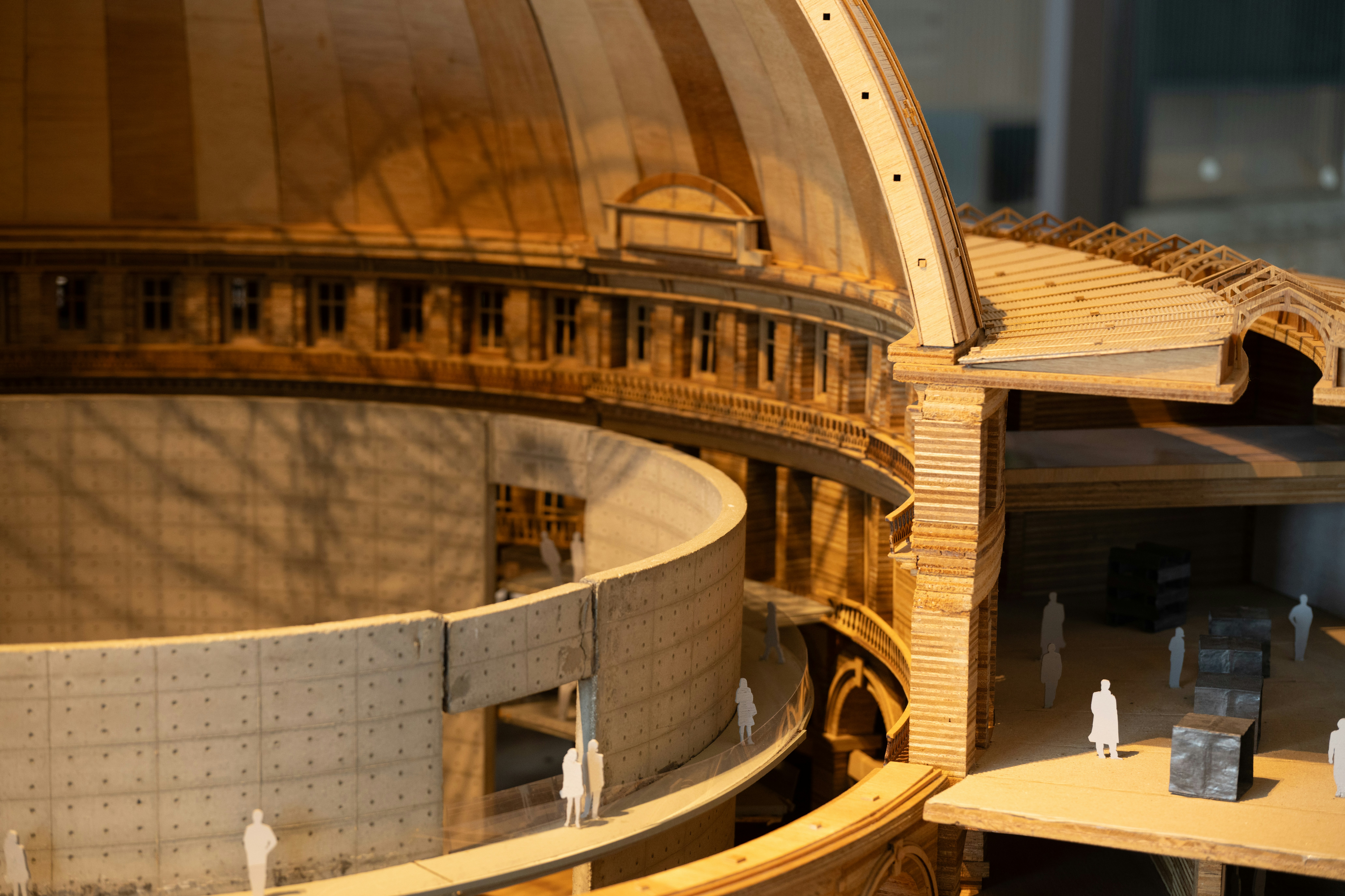 Um modelo arquitetônico de madeira de um edifício em cúpula com pequenas figuras de papel dentro