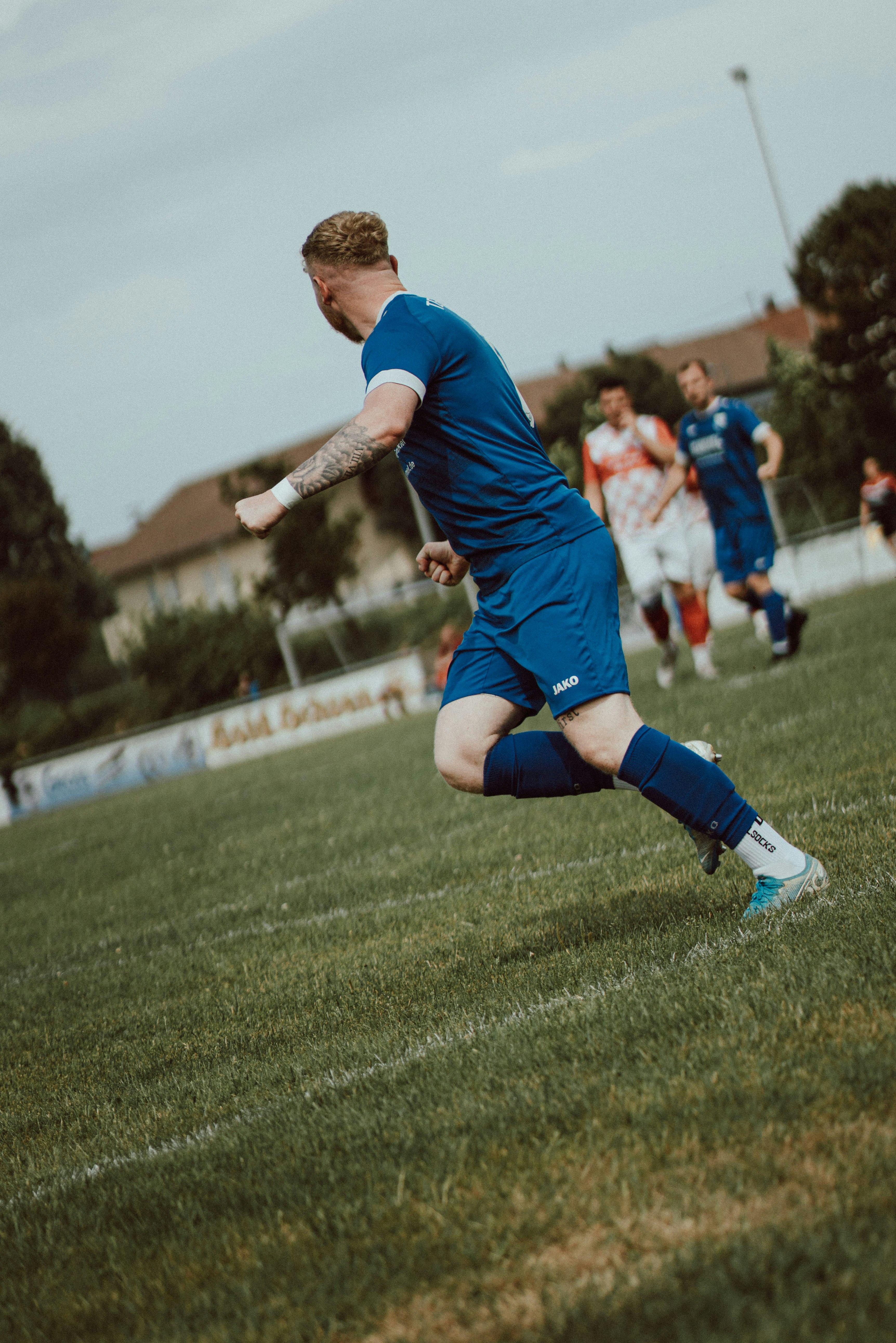 Ein Fußballspieler in blauem Trikot läuft über ein Rasenfeld