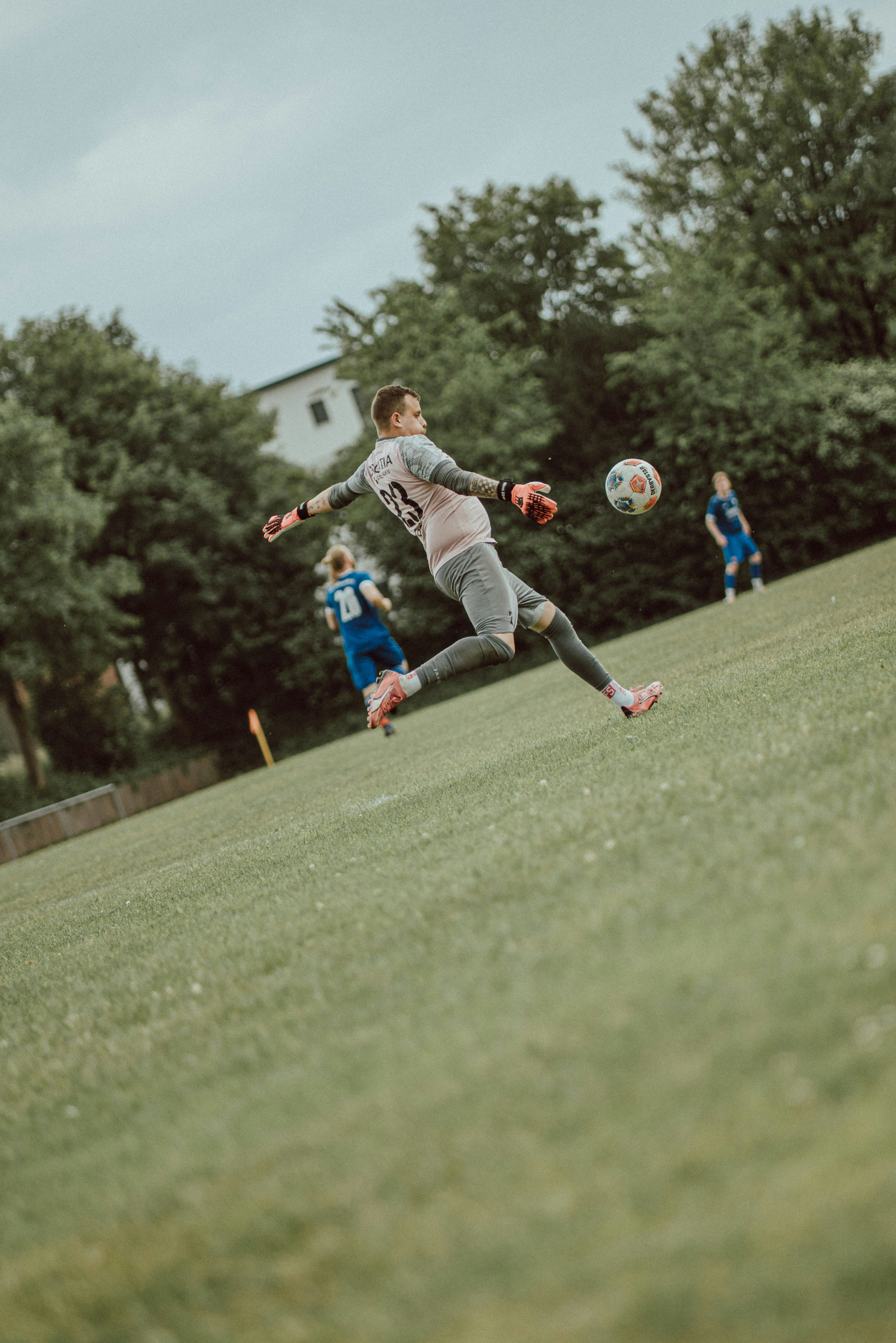 Ein Torwart, der während eines Spiels auf einem Rasenfeld einen Fußball kickt