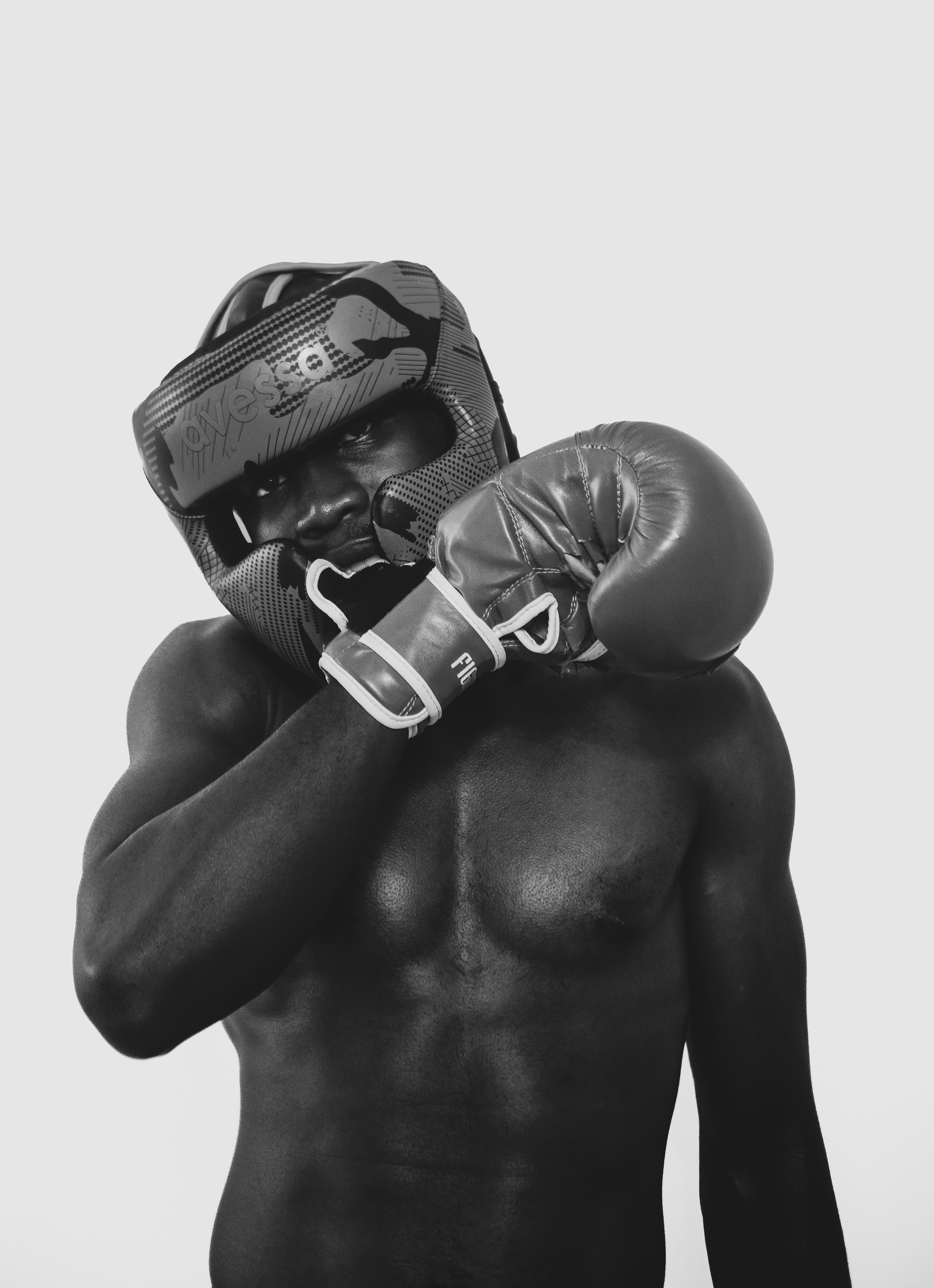 A shirtless man wearing a boxing headguard and a glove on one hand