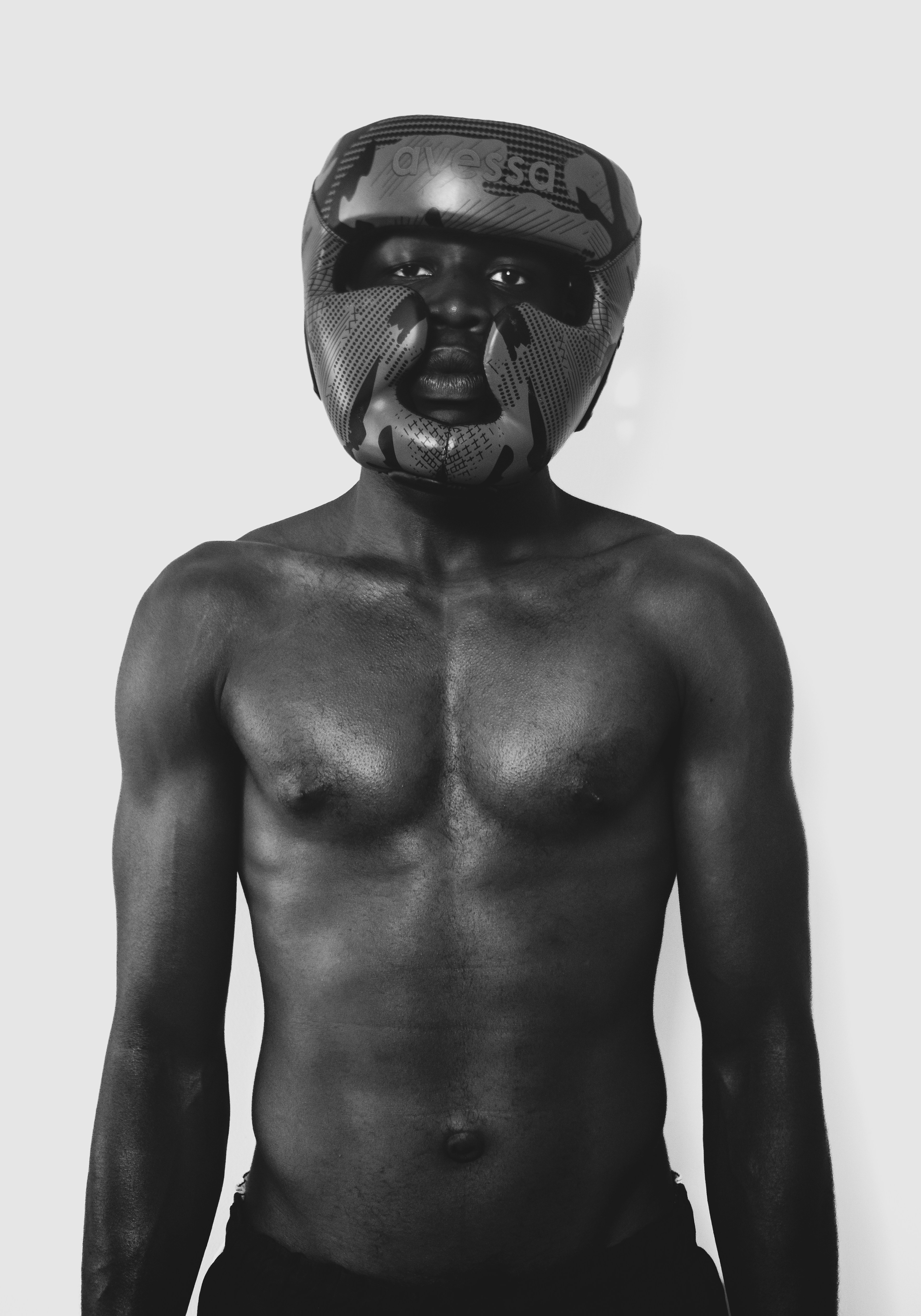 A shirtless person wearing a black boxing headgear against a plain white background