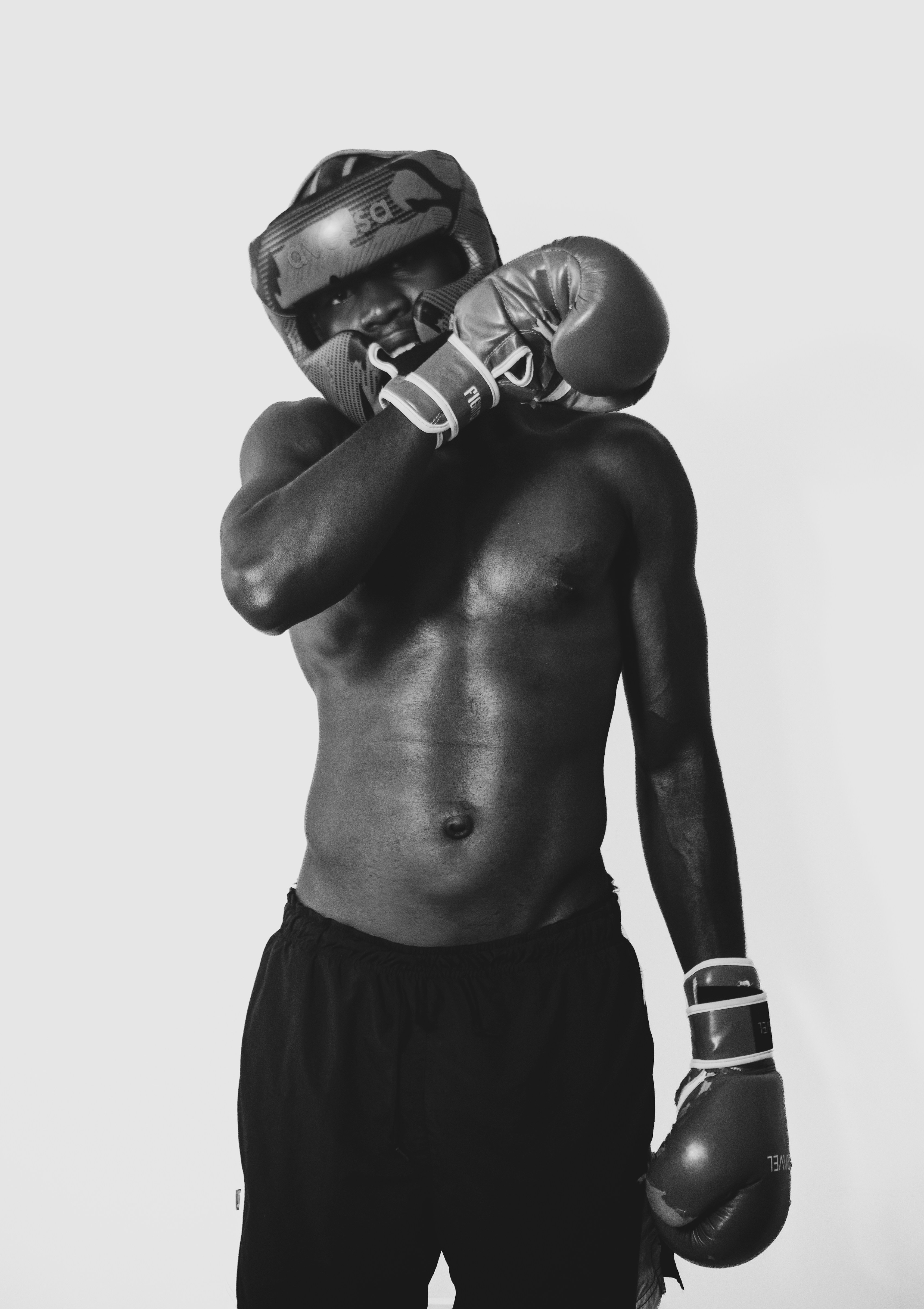 A shirtless boxer wearing headgear and gloves in a black and white portrait