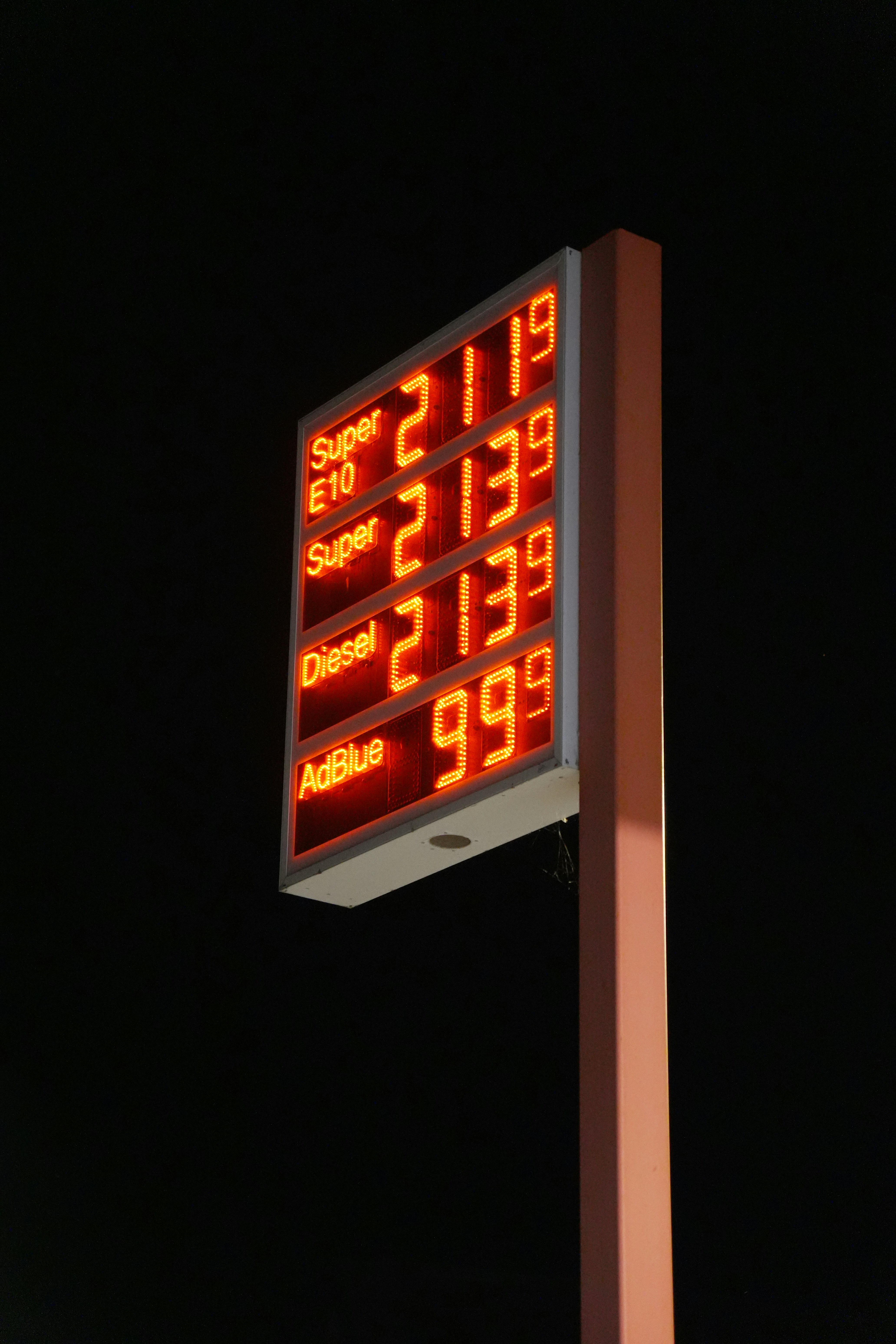 A glowing red digital fuel price sign against a dark night sky