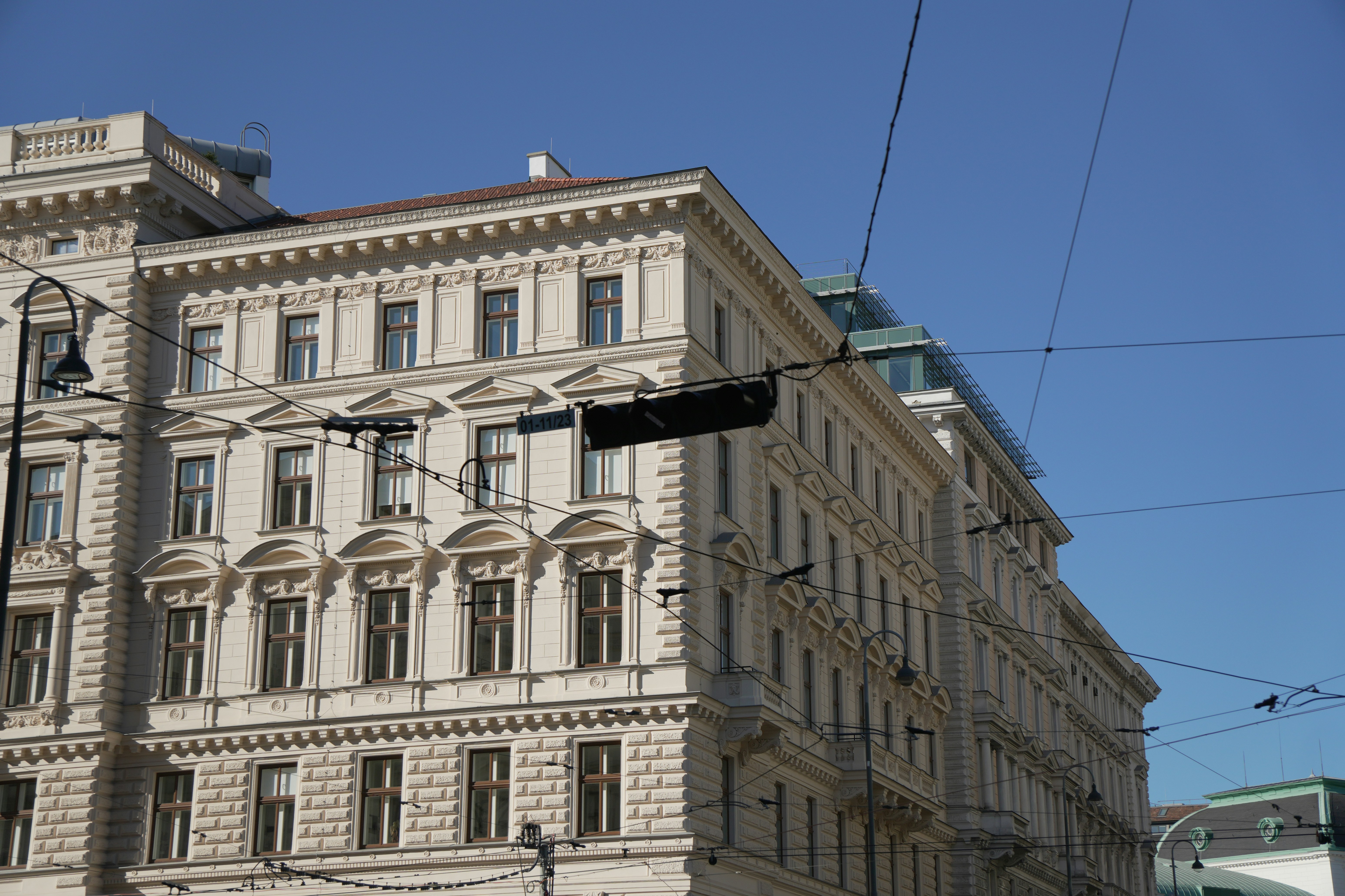 A neoclassical building with ornate white facade details under a clear blue sky