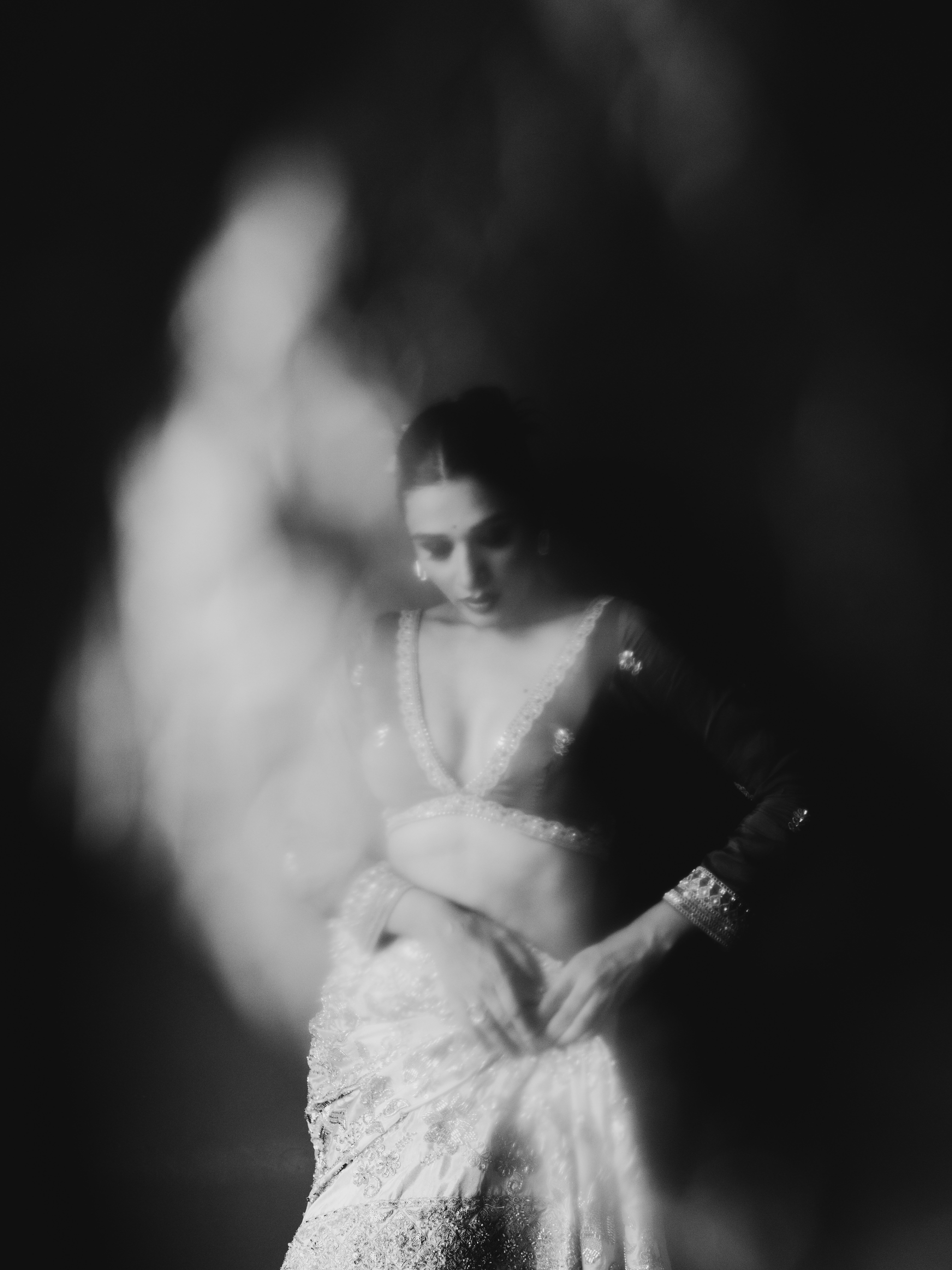 A woman in a traditional embroidered lehenga with a soft bokeh foreground effect