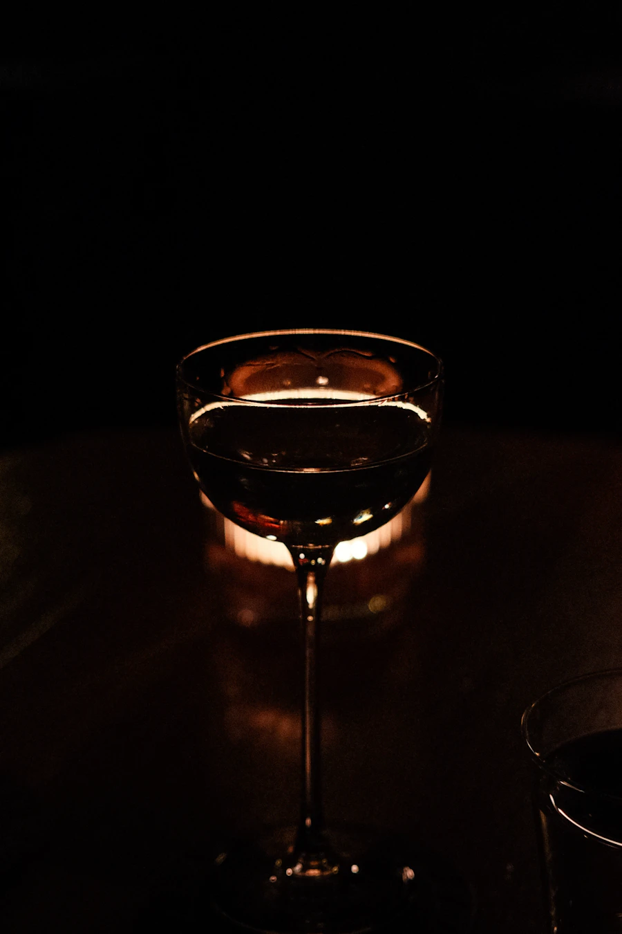 A stemmed glass lit from behind by a candle