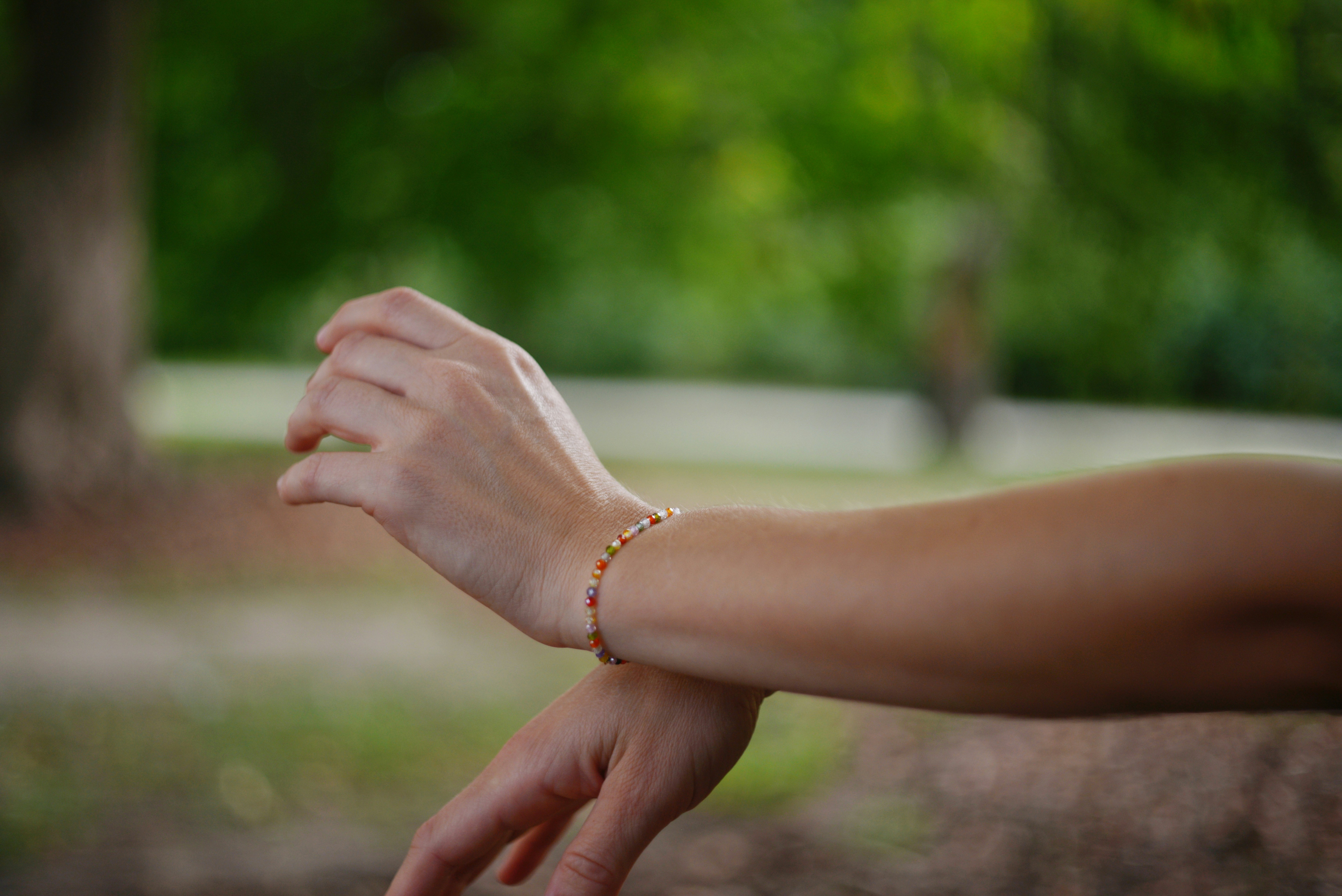 A person wearing a delicate beaded bracelet on their wrist in a park