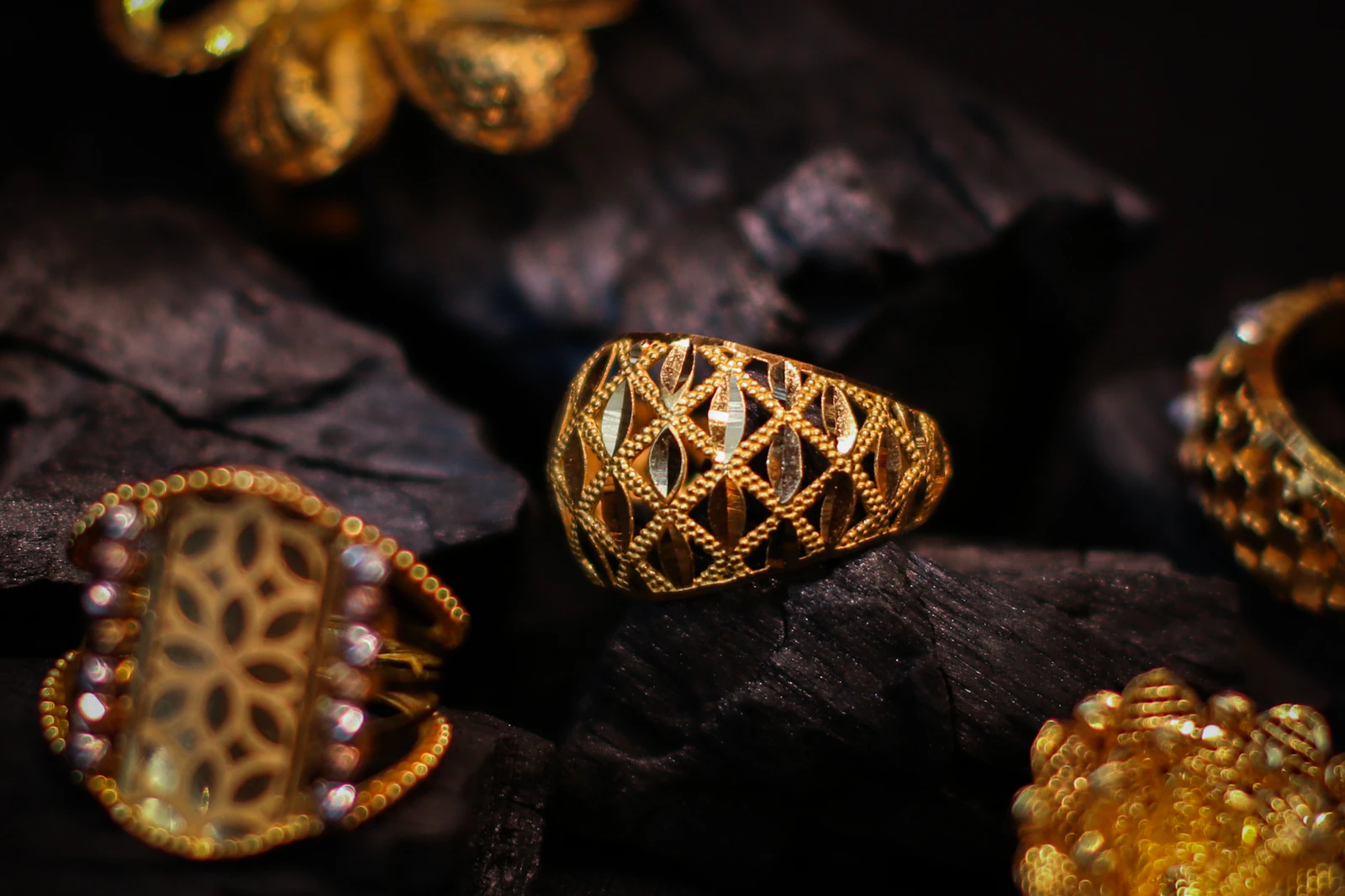 Sculpted yellow gold rings with lattice detail resting on dark stone