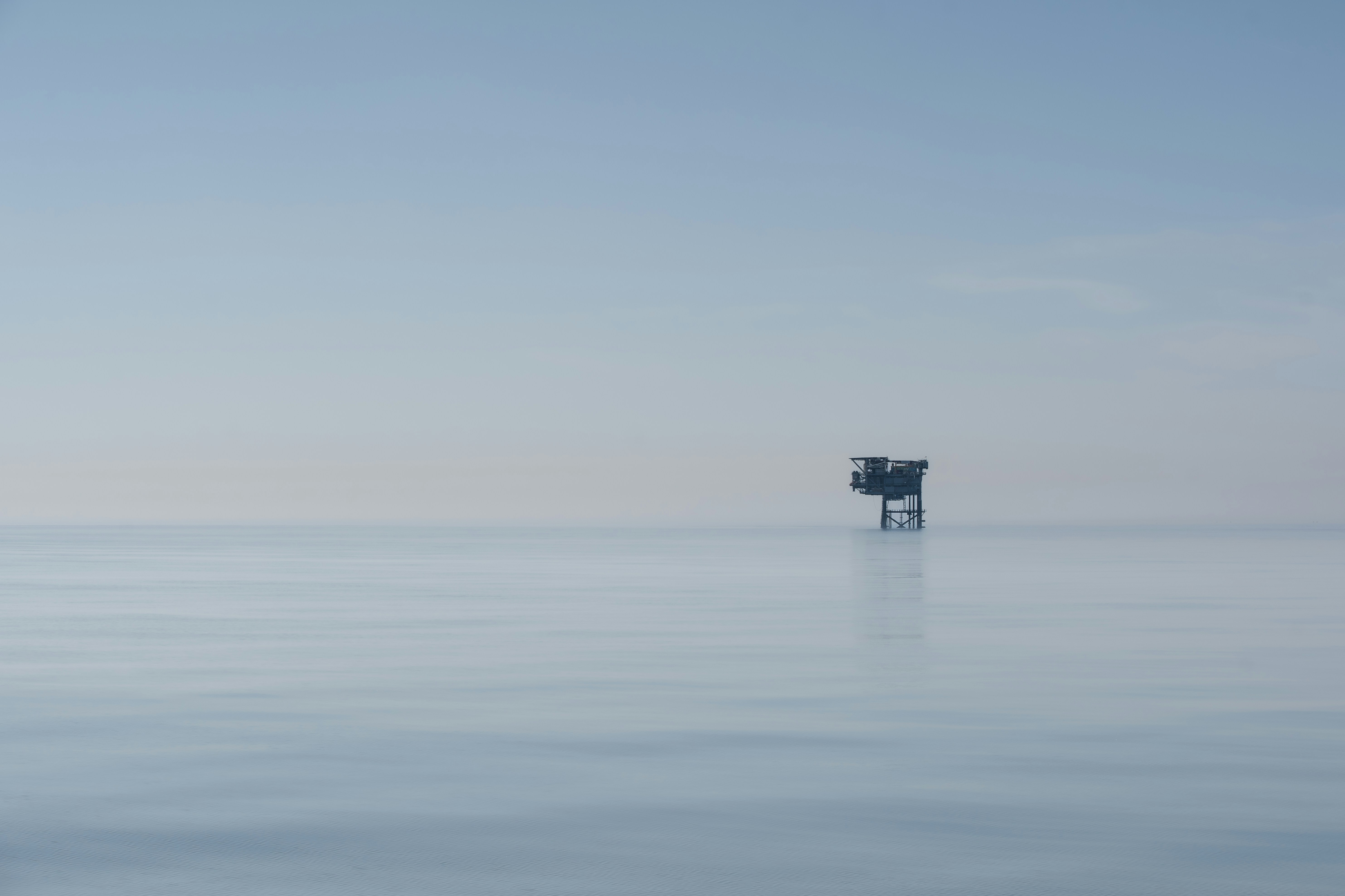 Uma pequena plataforma petrolífera offshore em um mar azul calmo e enevoado