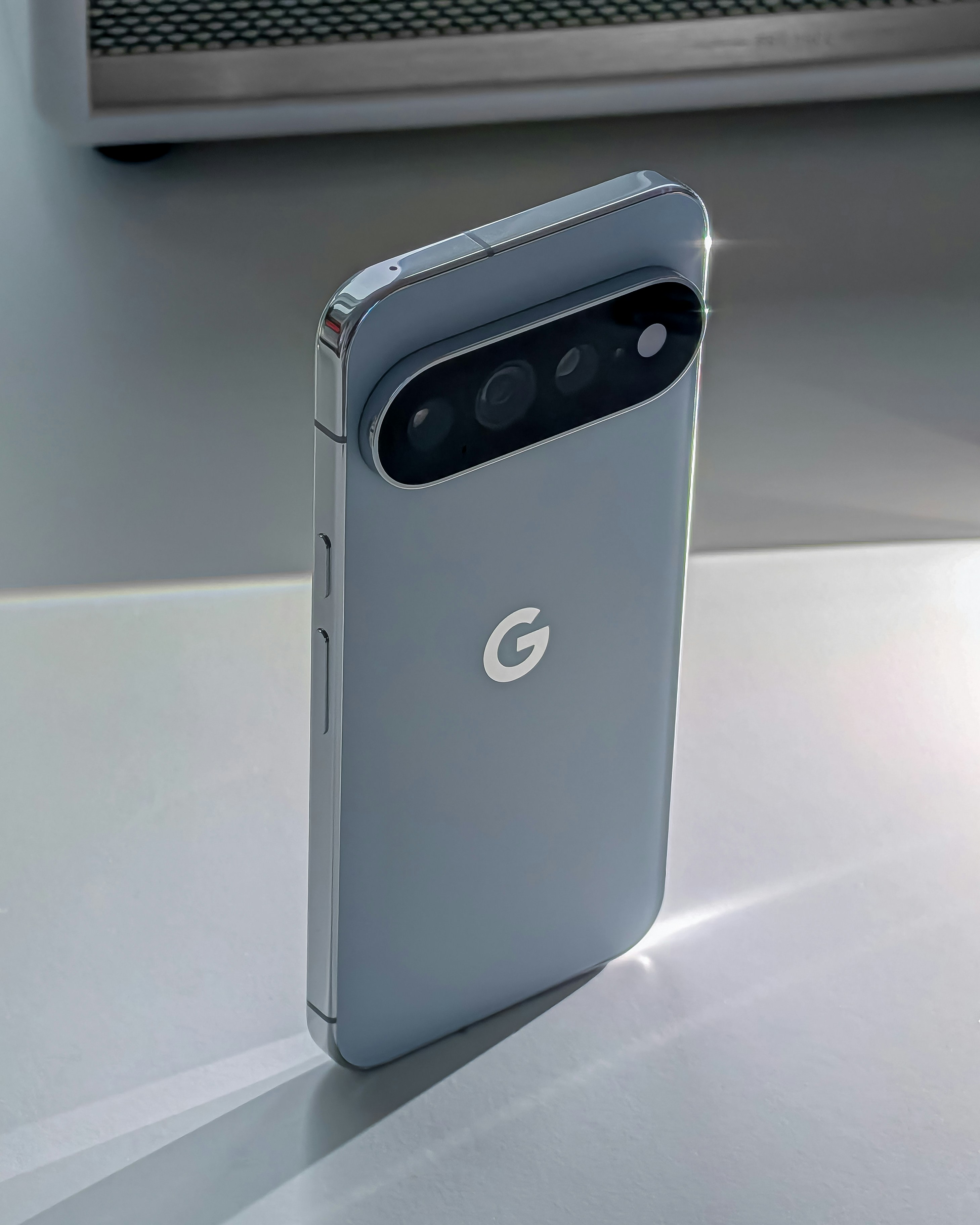 A light blue smartphone with a triple camera array on a white surface