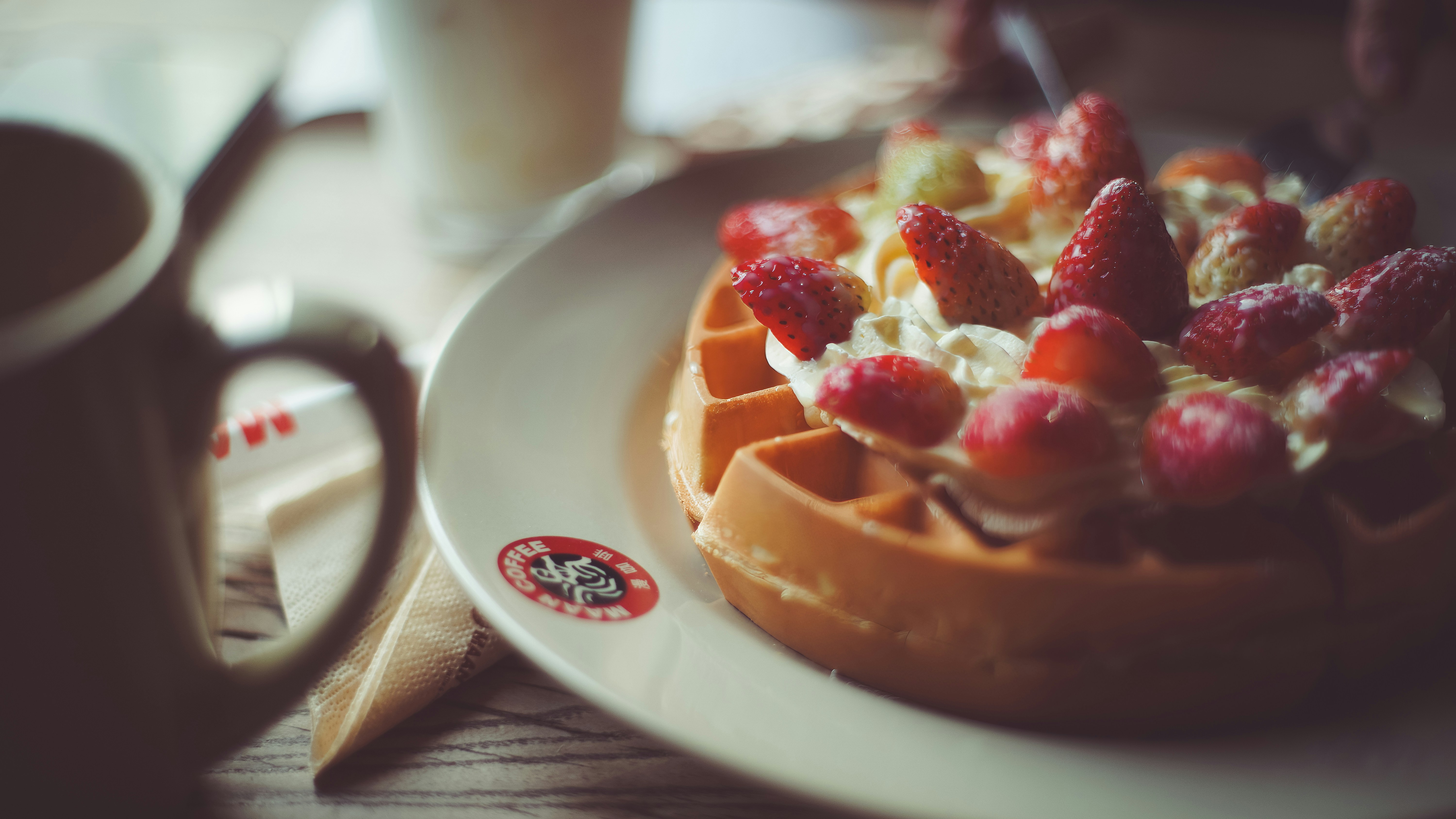 A waffle topped with whipped cream and fresh strawberries on a white plate