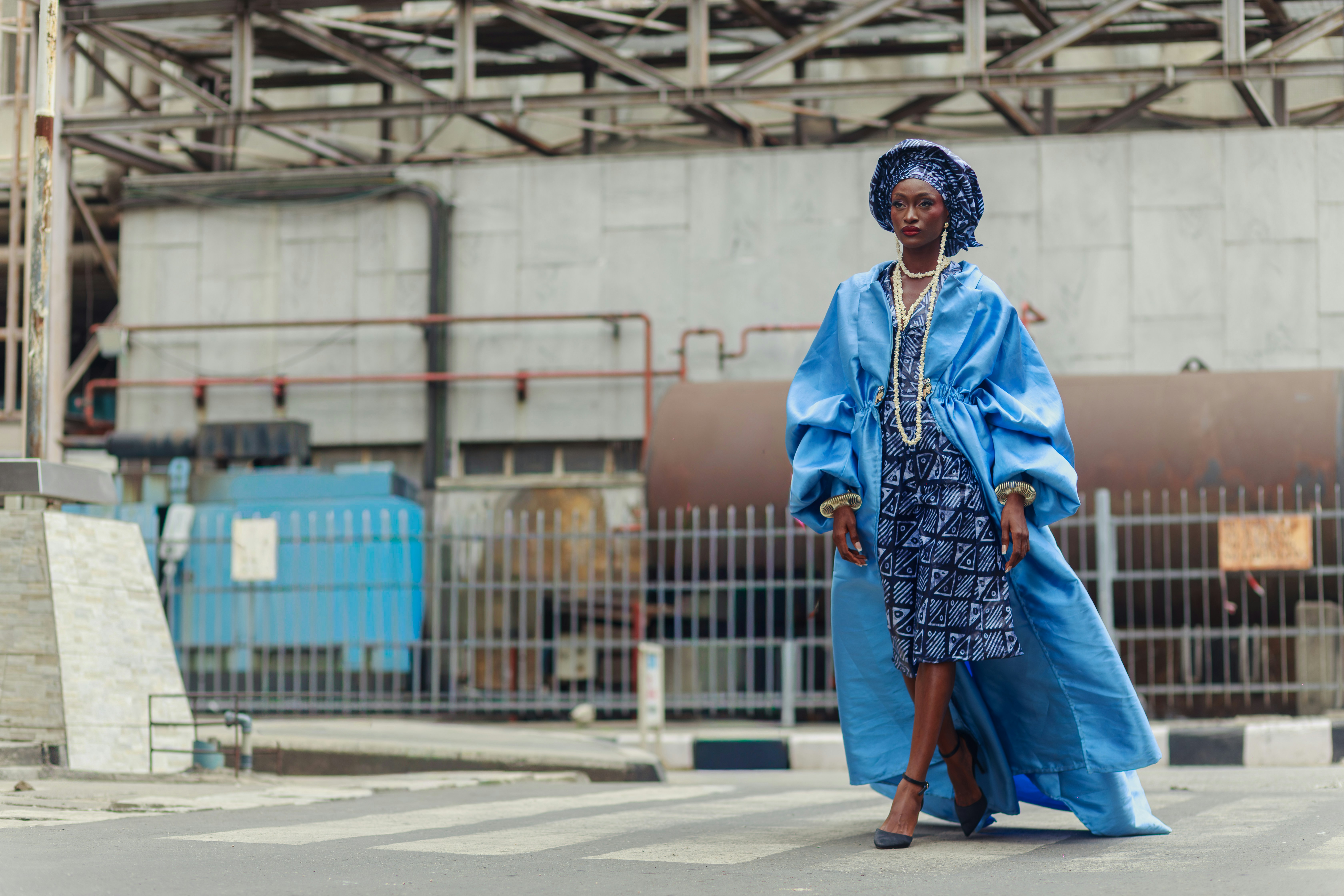 A woman in a blue coat and patterned dress walking in Lagos, Nigeria