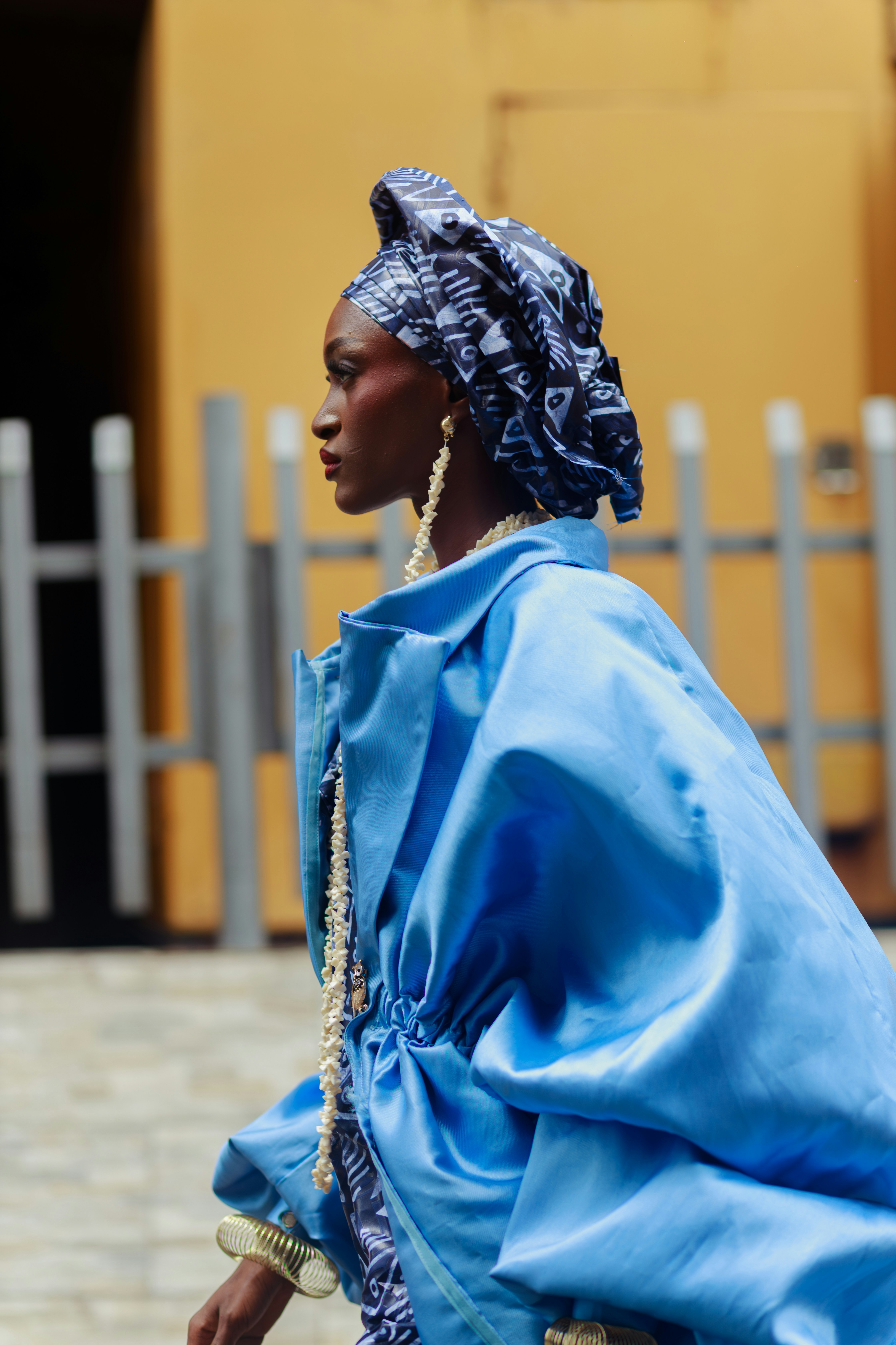 Uma mulher com um casaco azul brilhante e uma faixa de cabeça estampada em Lagos, Nigéria