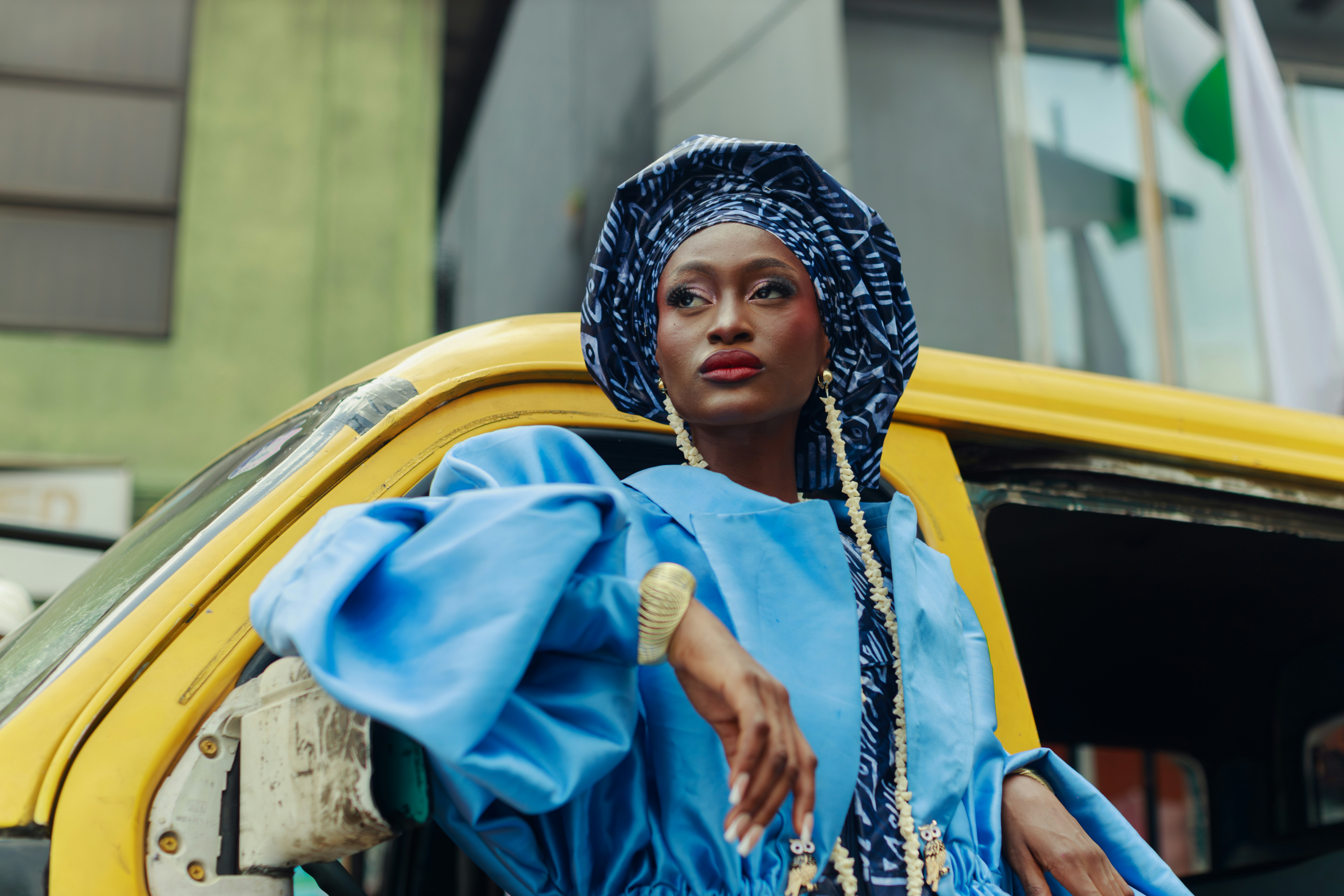 Uma mulher com roupa azul encostada em um ônibus amarelo em Lagos