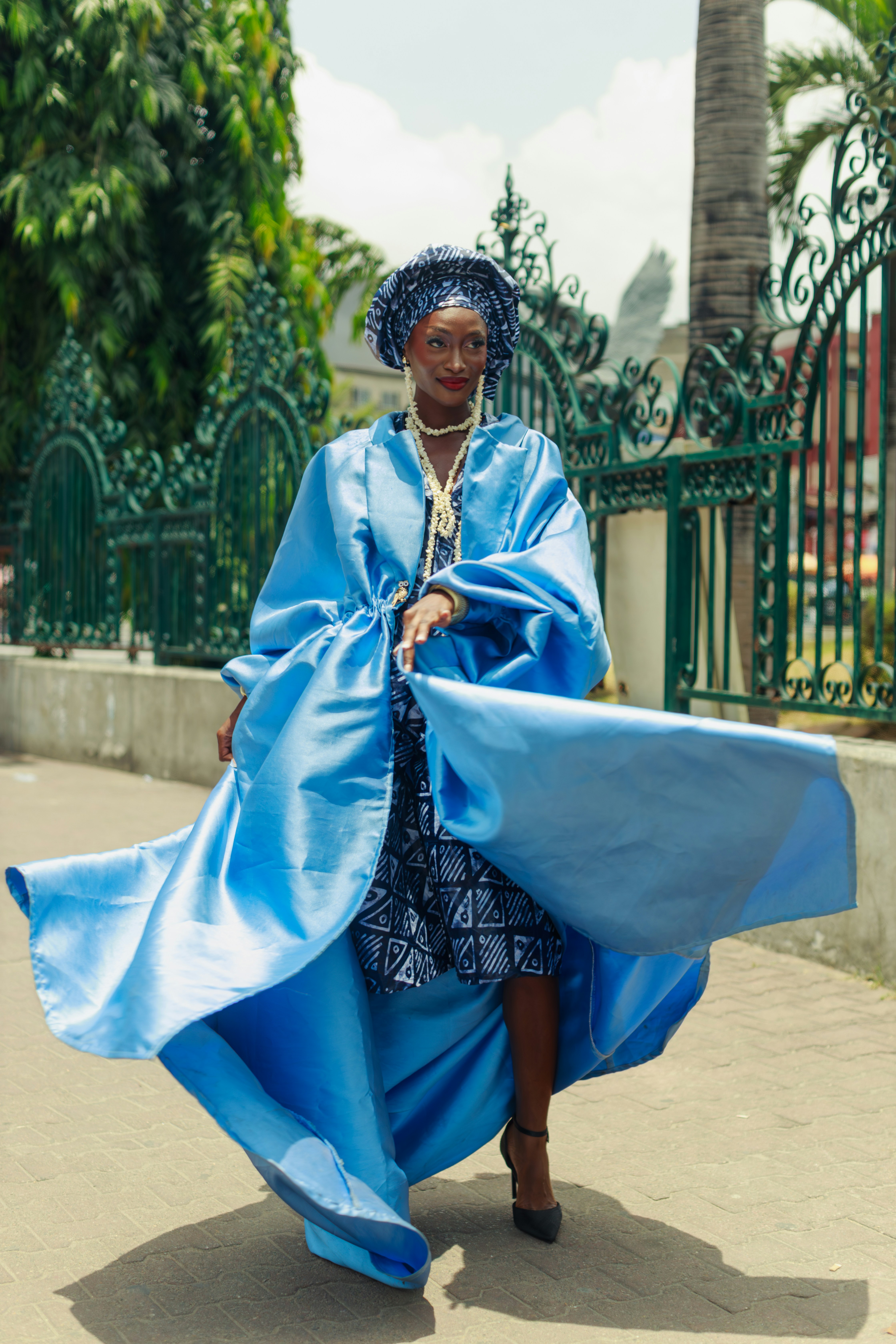 Uma mulher com um casaco de cetim azul e vestido estampado em Lagos, Nigéria