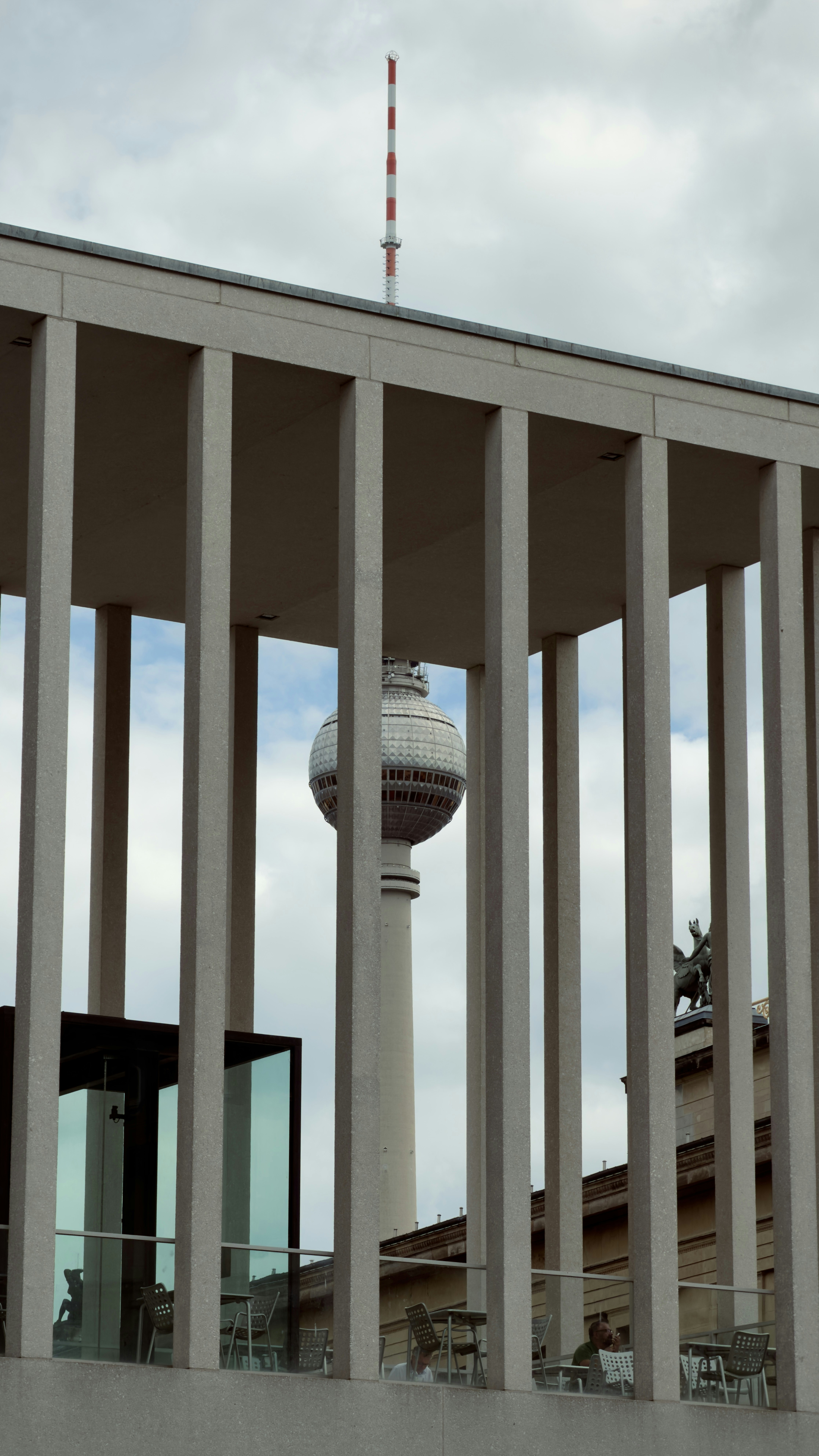 The Berlin TV Tower framed by concrete pillars of a modern building in Berlin