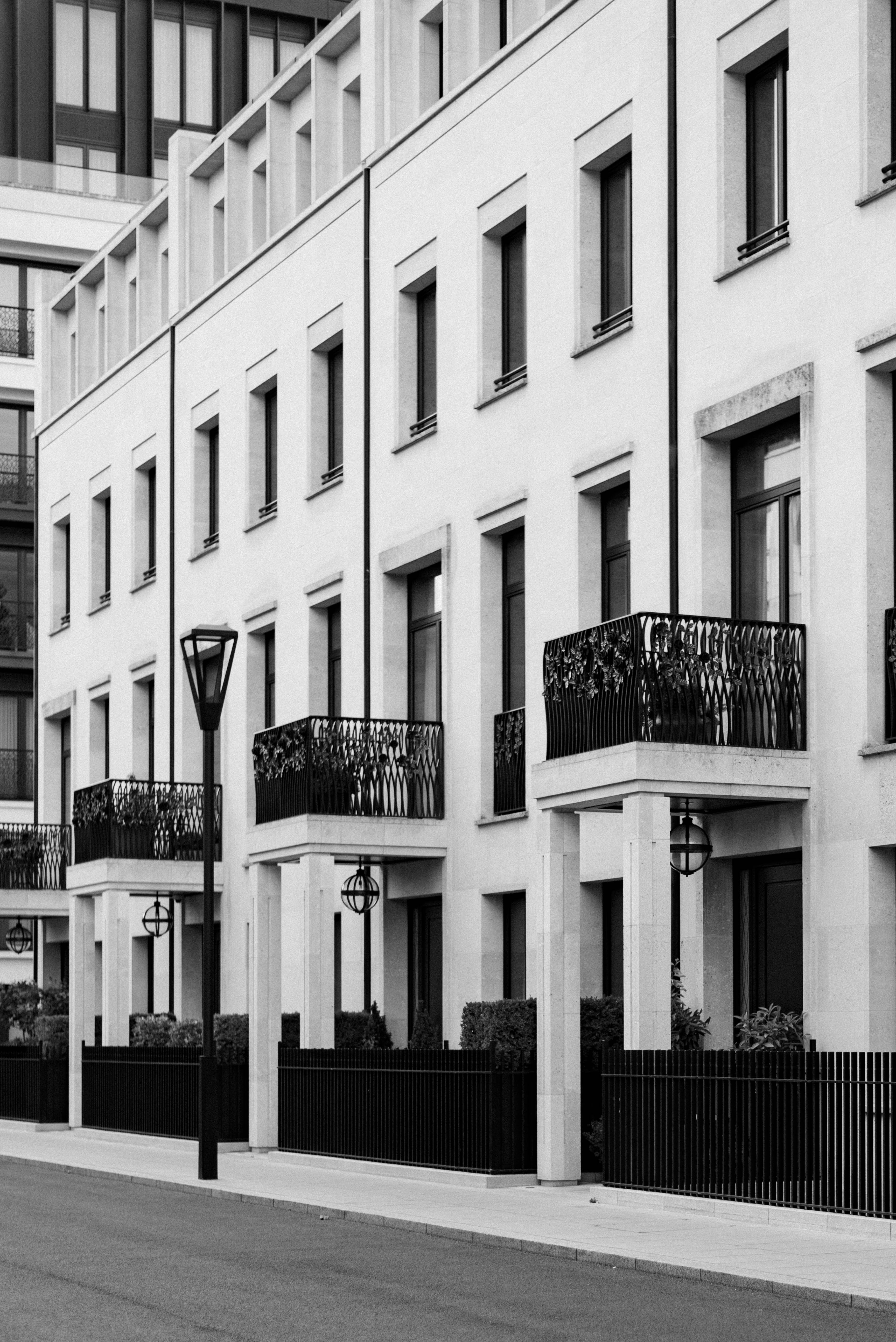 Row of white townhouses with black iron balconies and lanterns