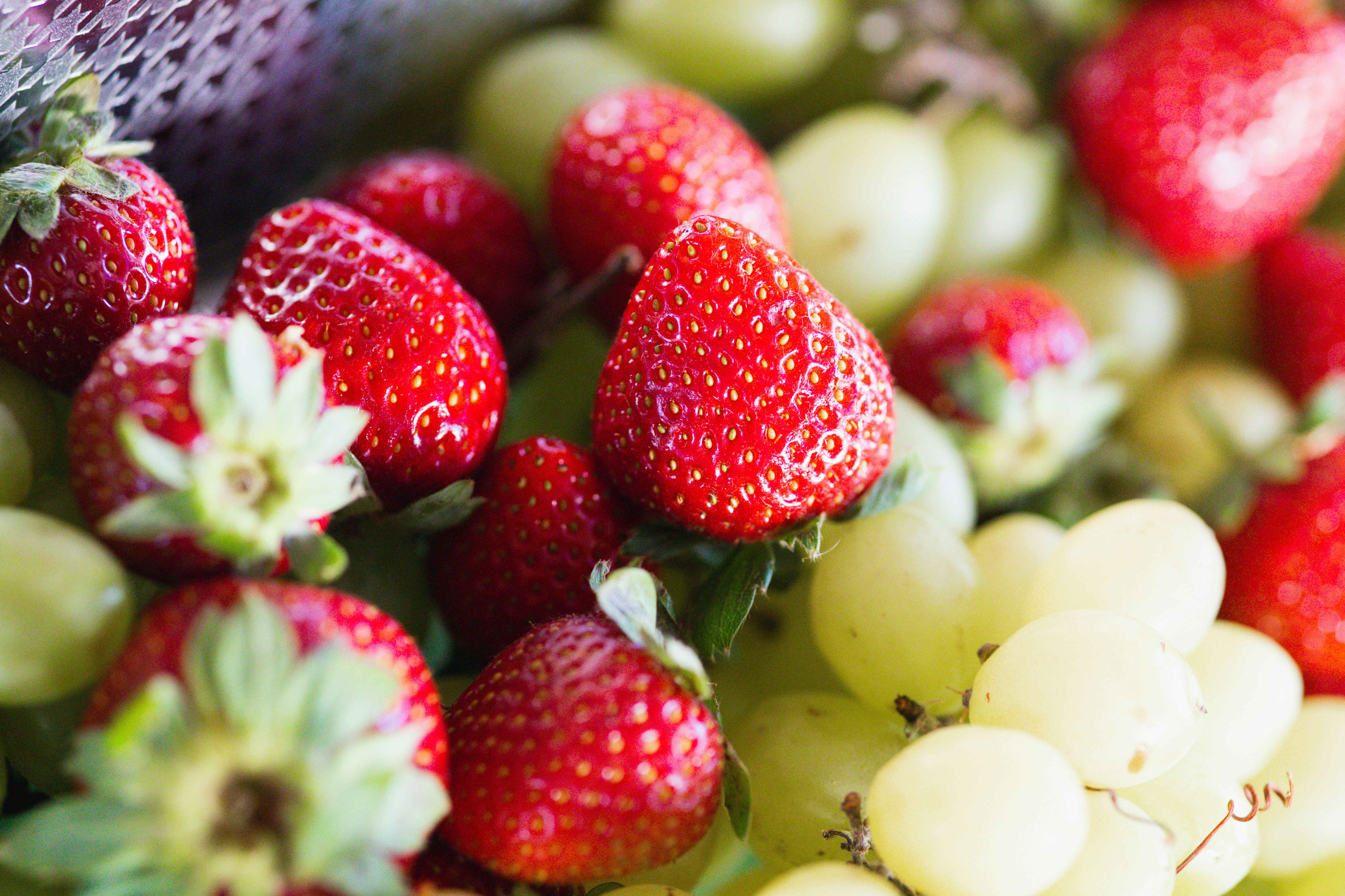 Fresh red strawberries and green grapes piled together in a close-up view