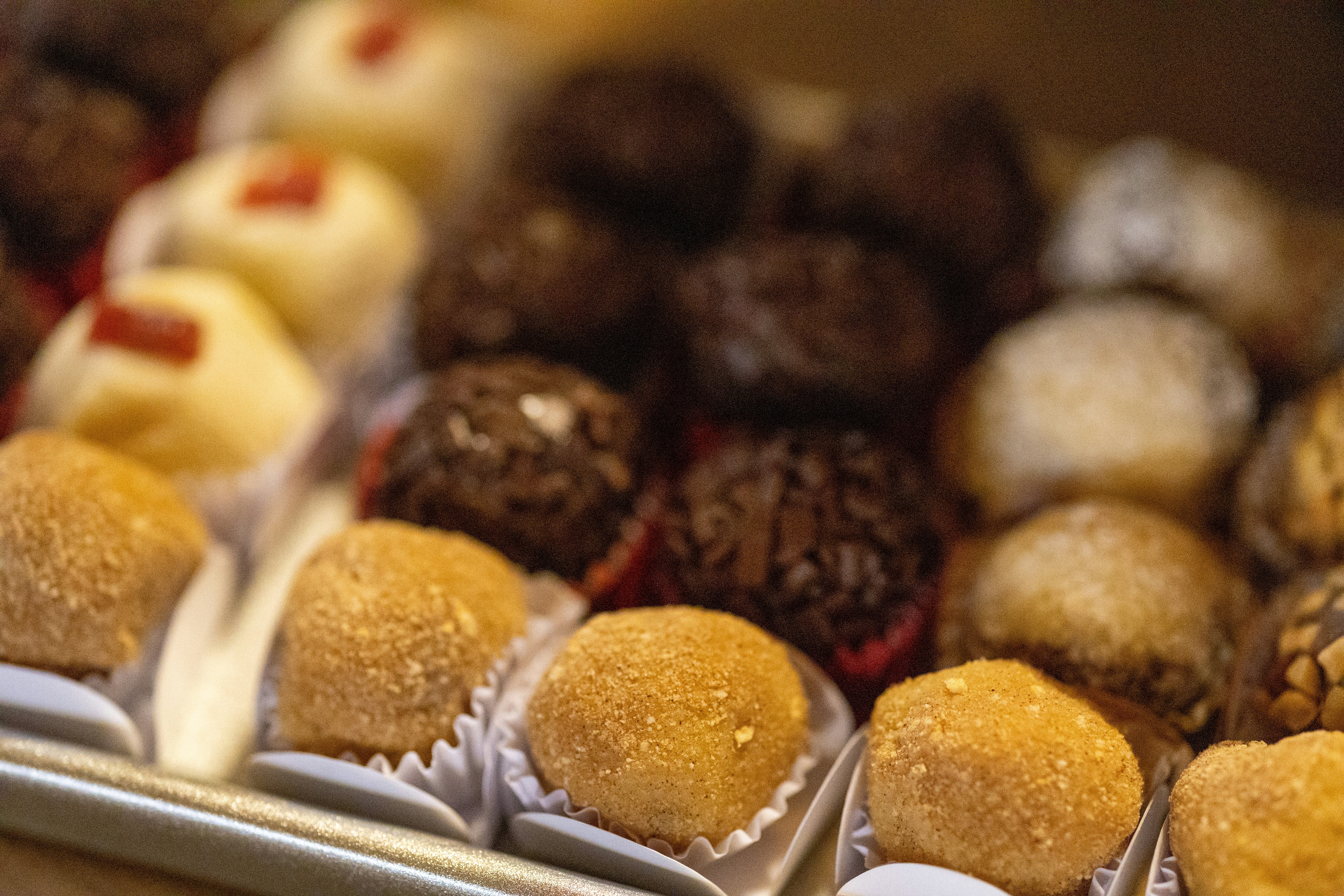 A variety of brigadeiros and truffles arranged in rows on a metal tray