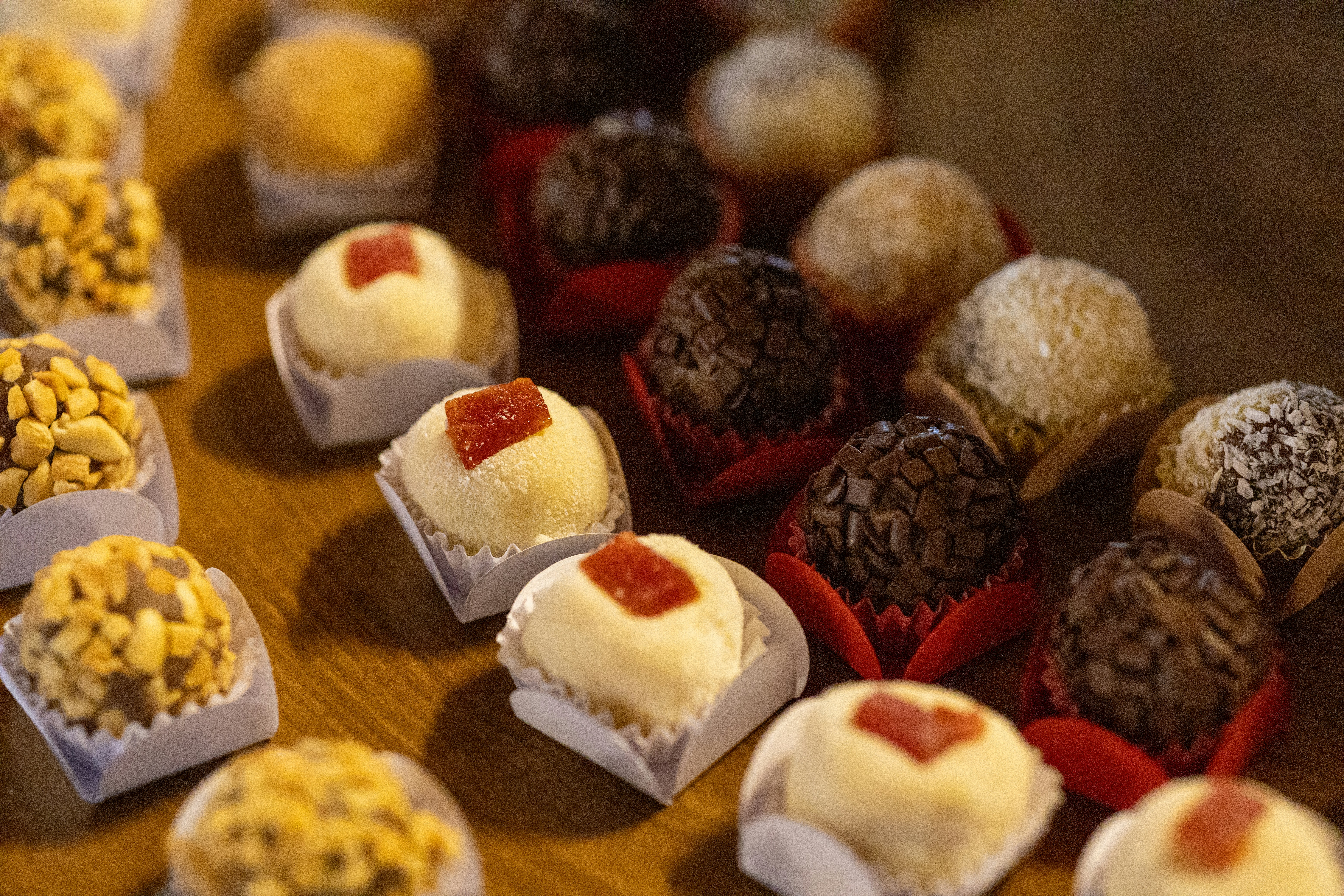 Assorted brigadeiros and white sweets with guava paste on a wooden table