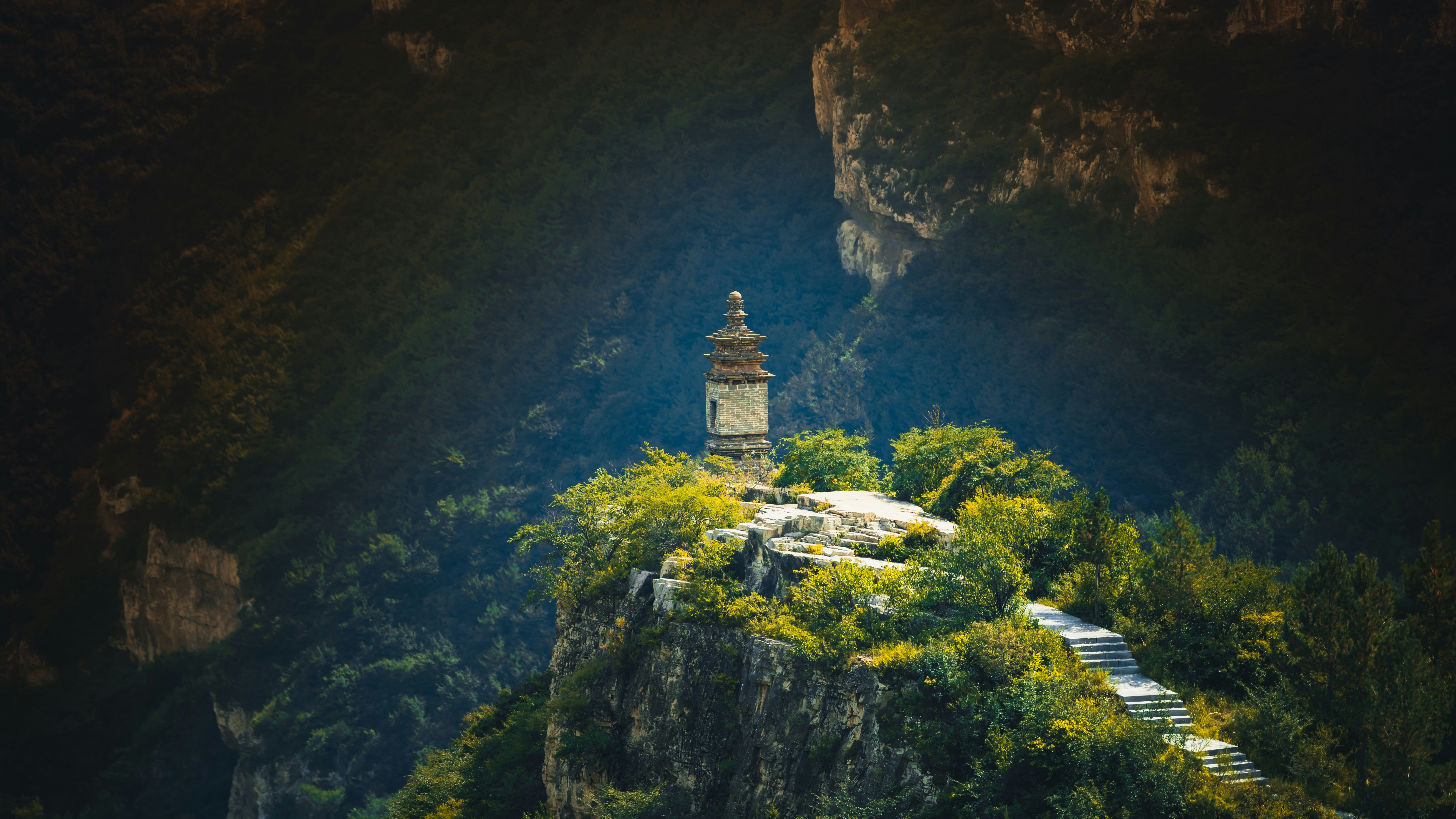 Uma pagode de pedra em um penhasco rochoso com uma escada que leva para cima