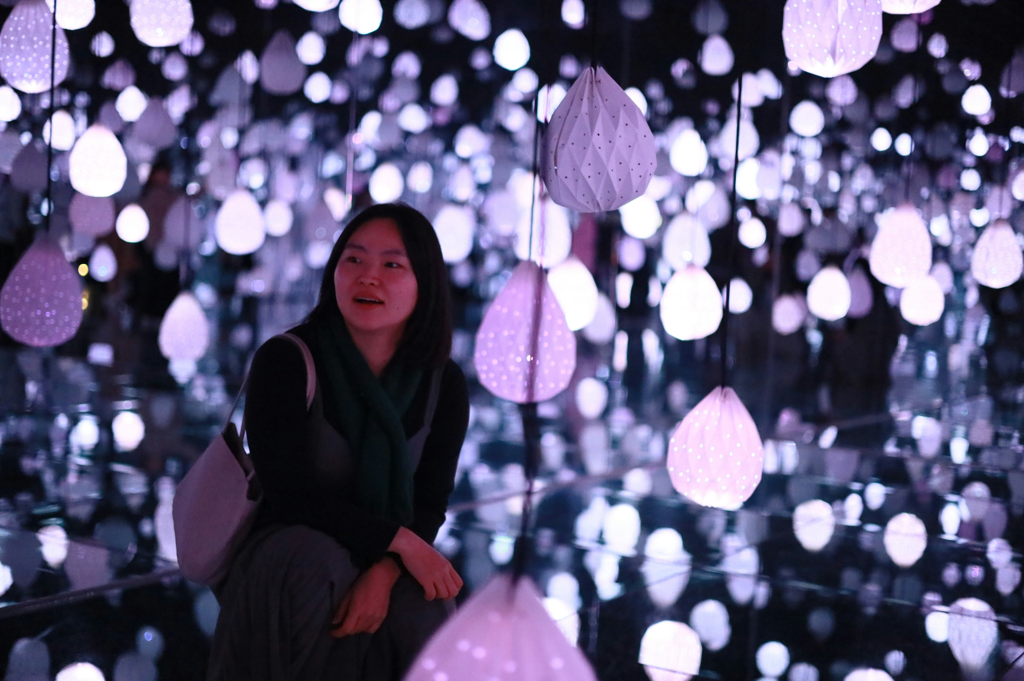 Visiteuse au milieu de lanternes lumineuses suspendues, une ambiance proche des installations d'art asiatique de la semaine de l'art à Paris