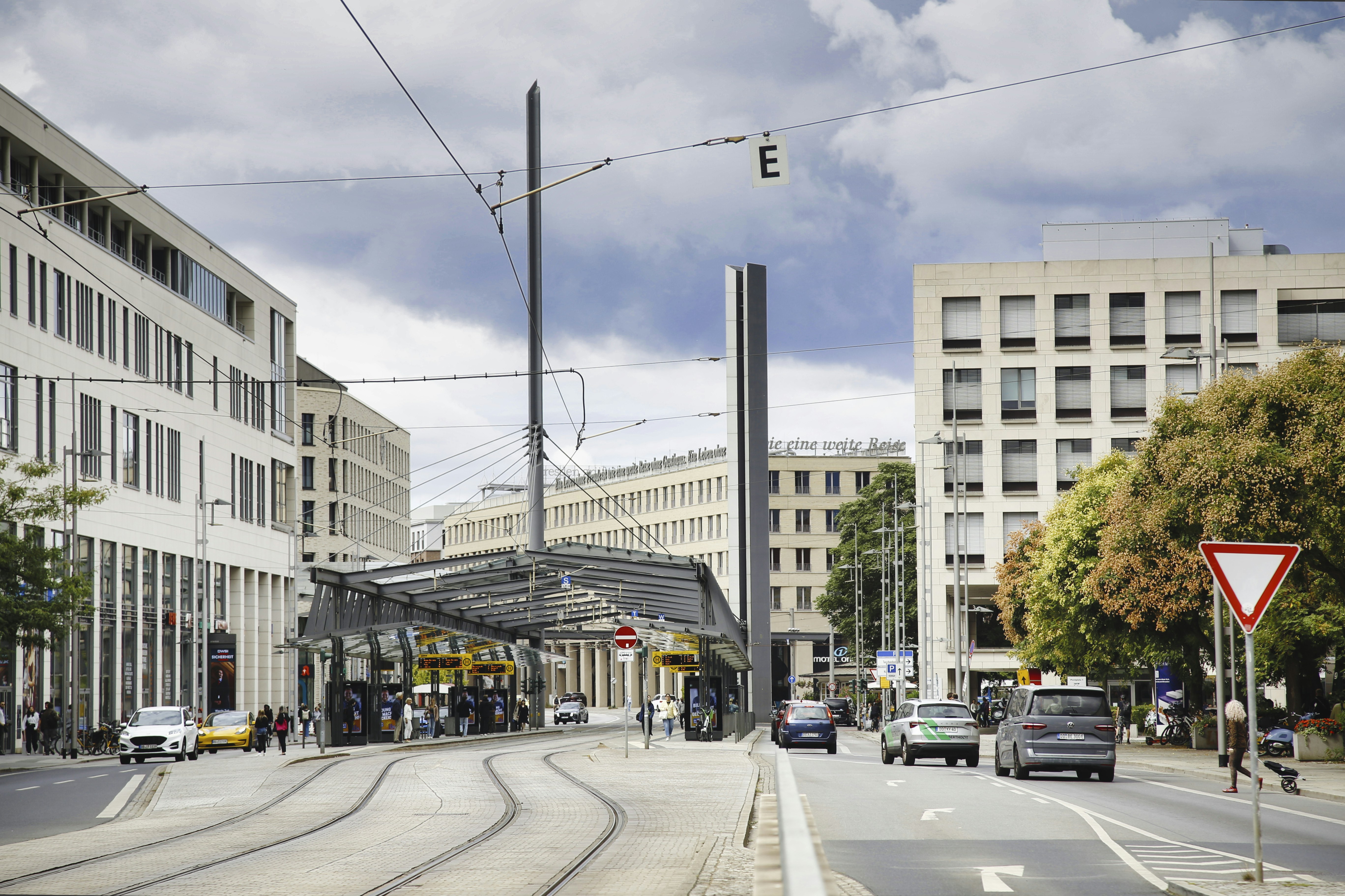 Tram tracks running through a modern city street with cars and a station canopy