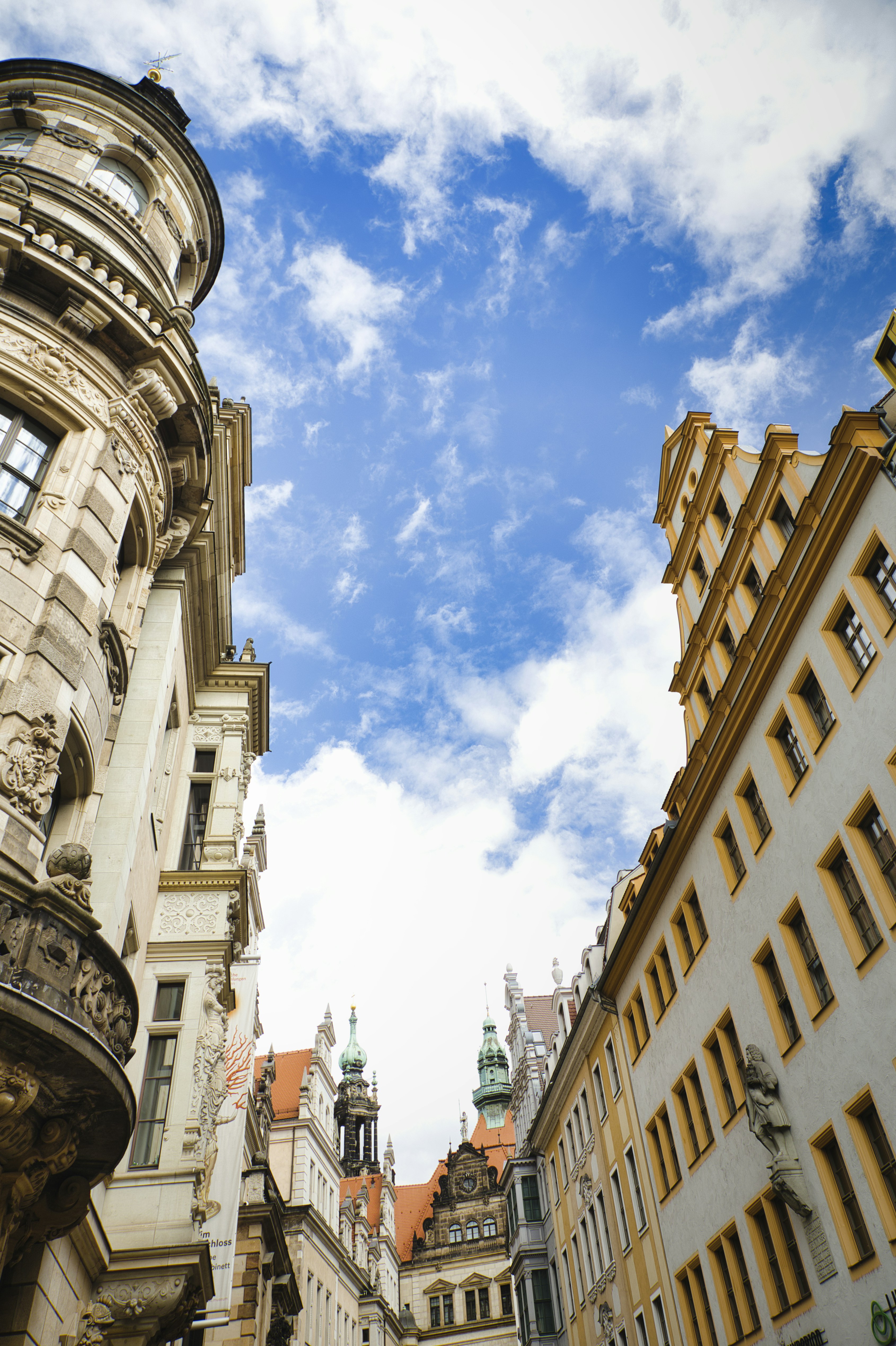Ornate historic buildings with yellow trim under a bright blue sky with clouds
