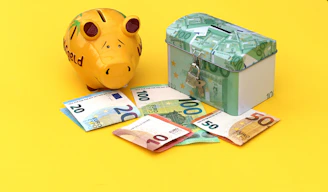 A yellow piggy bank and a locked metal box with euro banknotes on yellow
