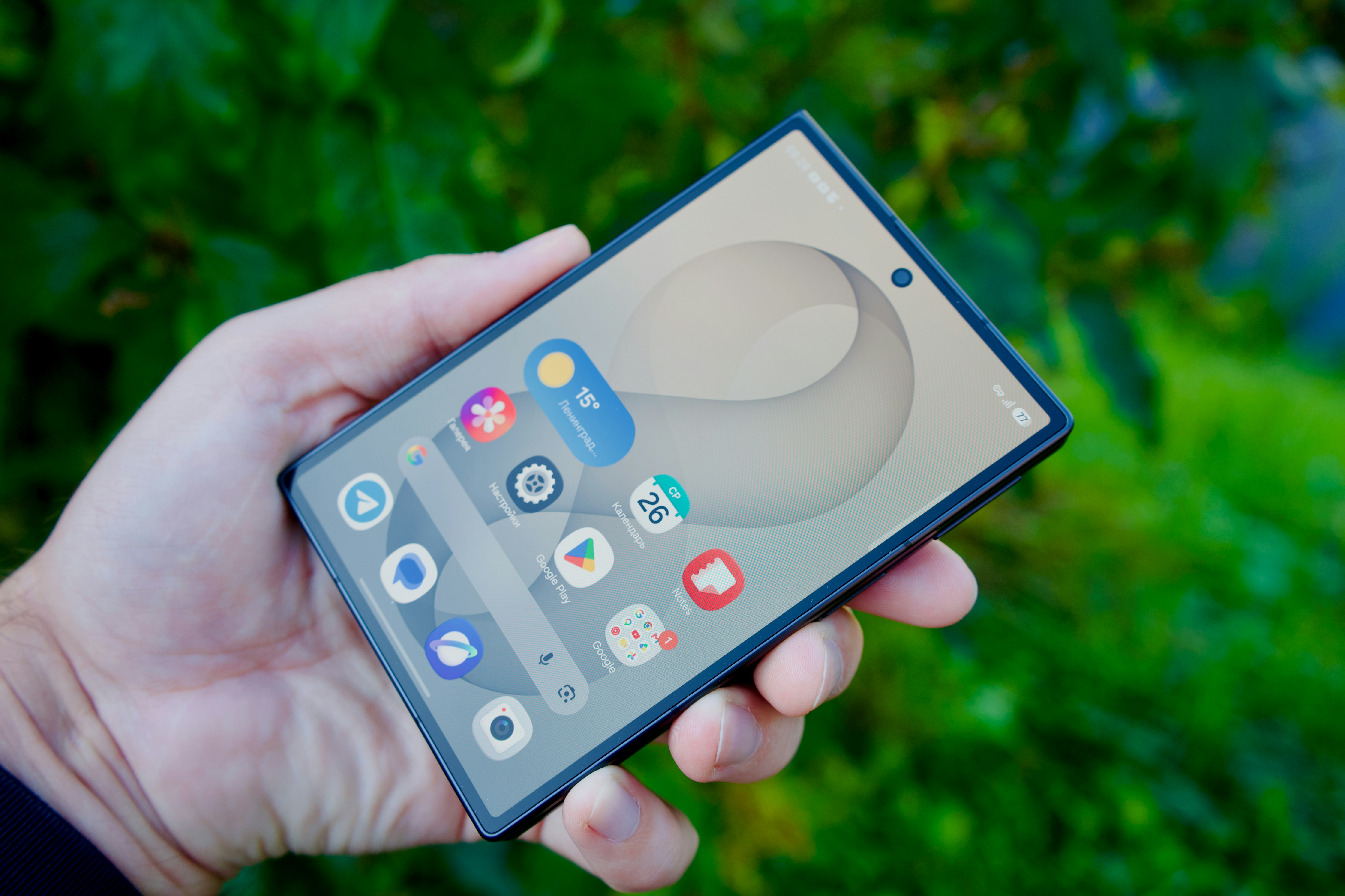 A hand holding a smartphone with a digital interface against a green background
