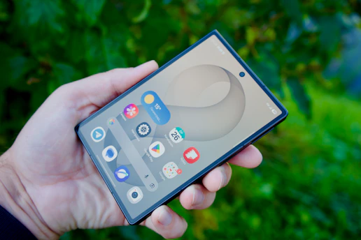 A hand holding a smartphone with a digital interface against a green background