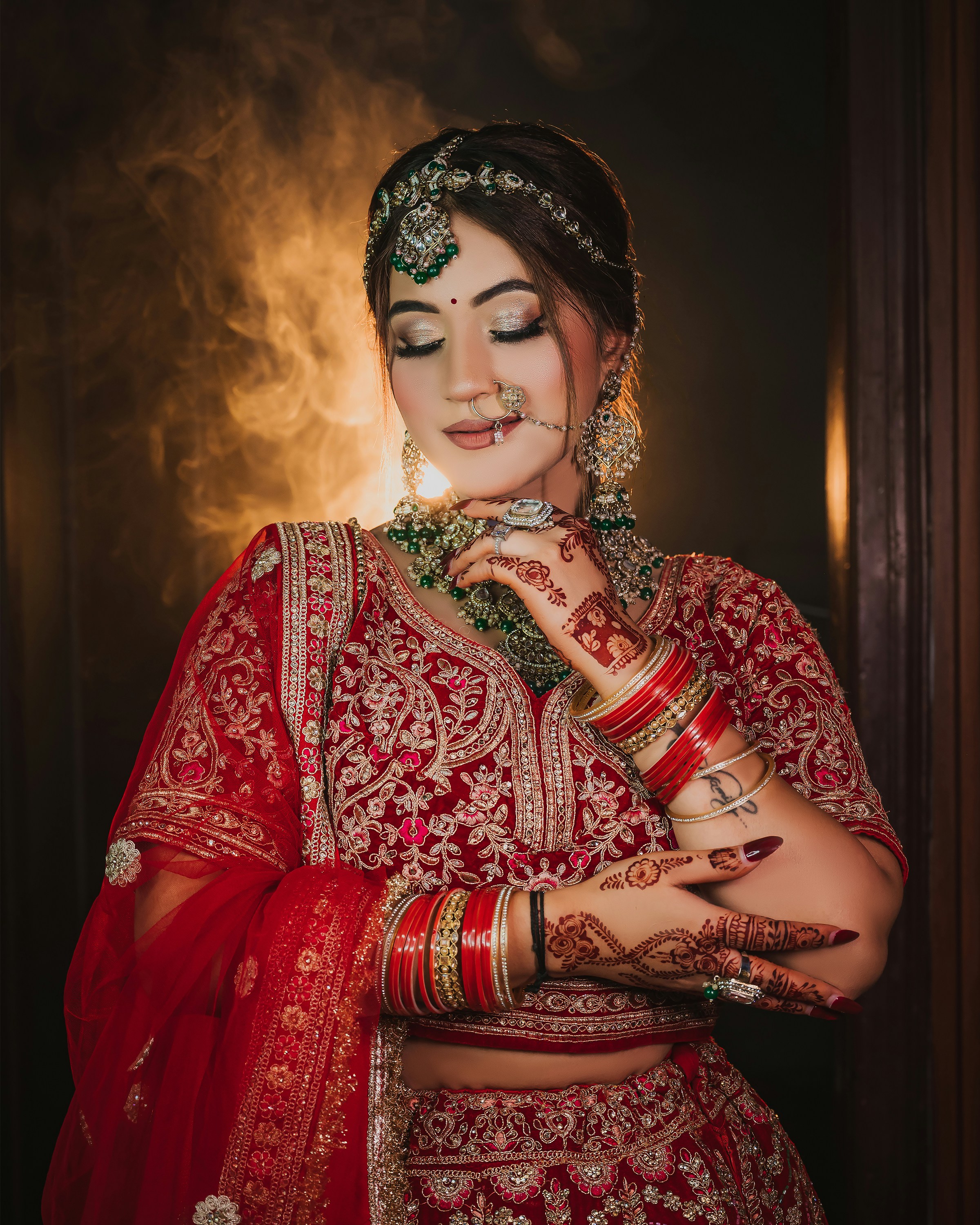 A woman in a red embroidered lehenga with henna patterns and gold jewelry
