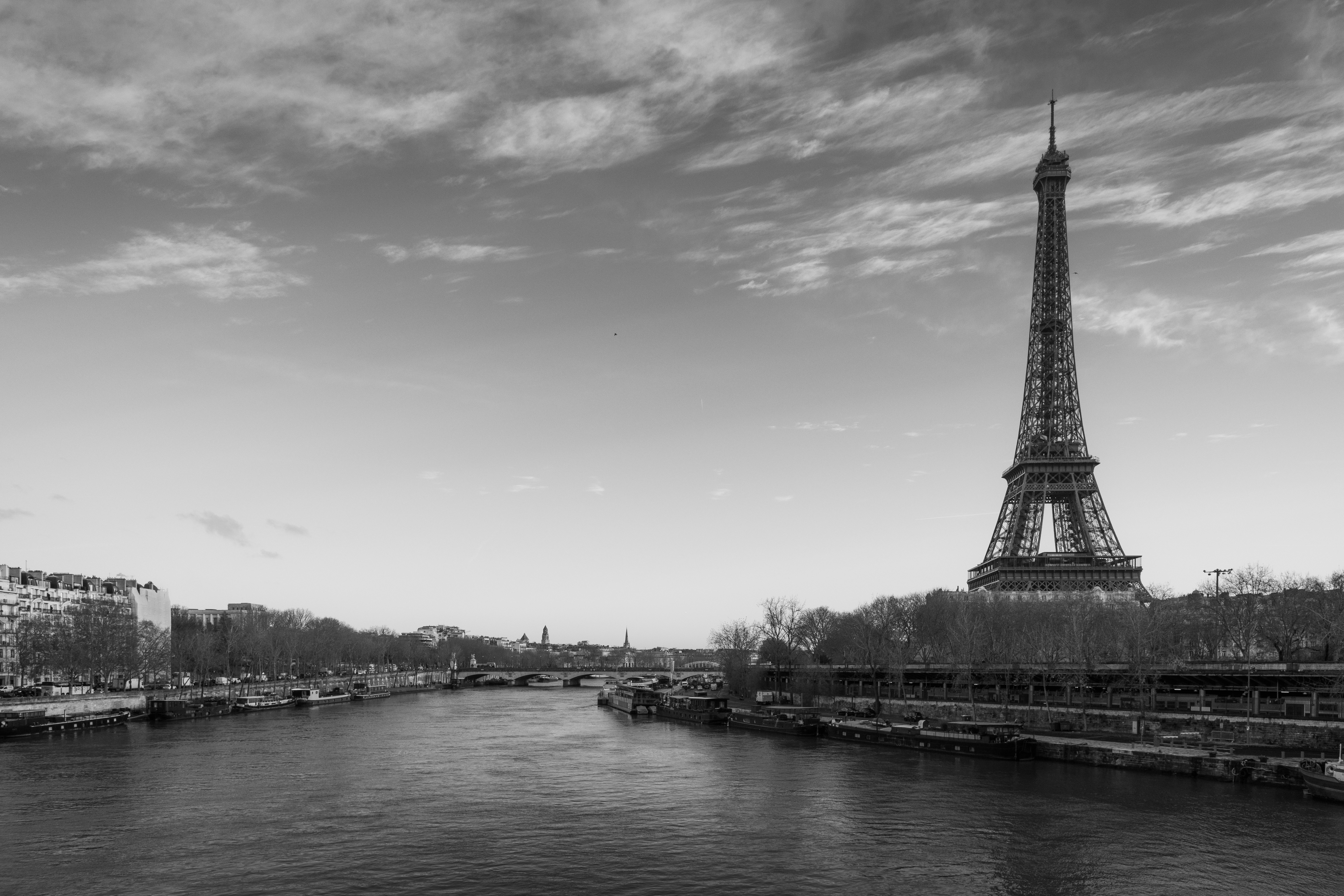 The Eiffel Tower rising above the Seine river in Paris under a cloudy sky
