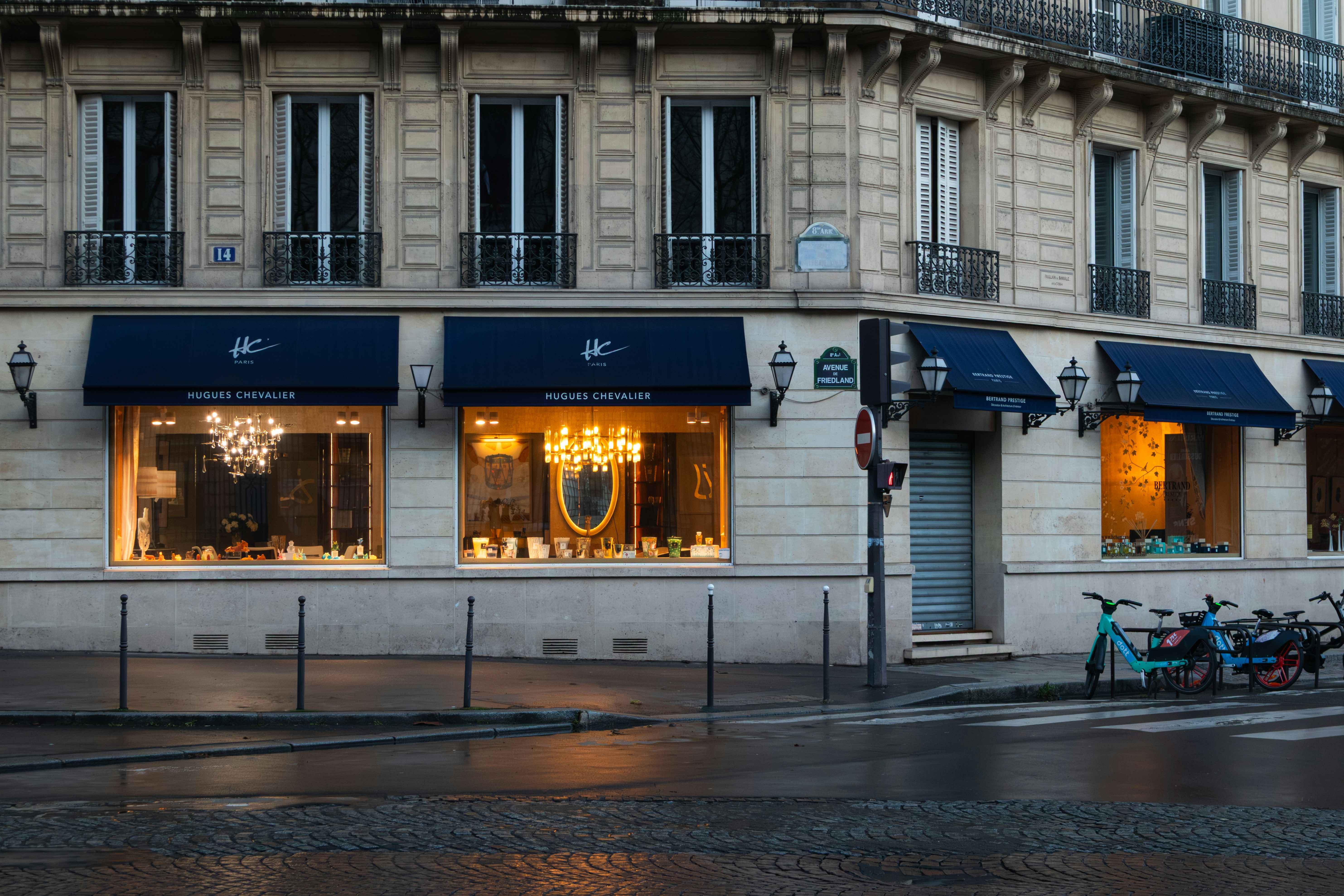 A storefront with blue awnings and lit windows on Avenue de Friedland in Paris