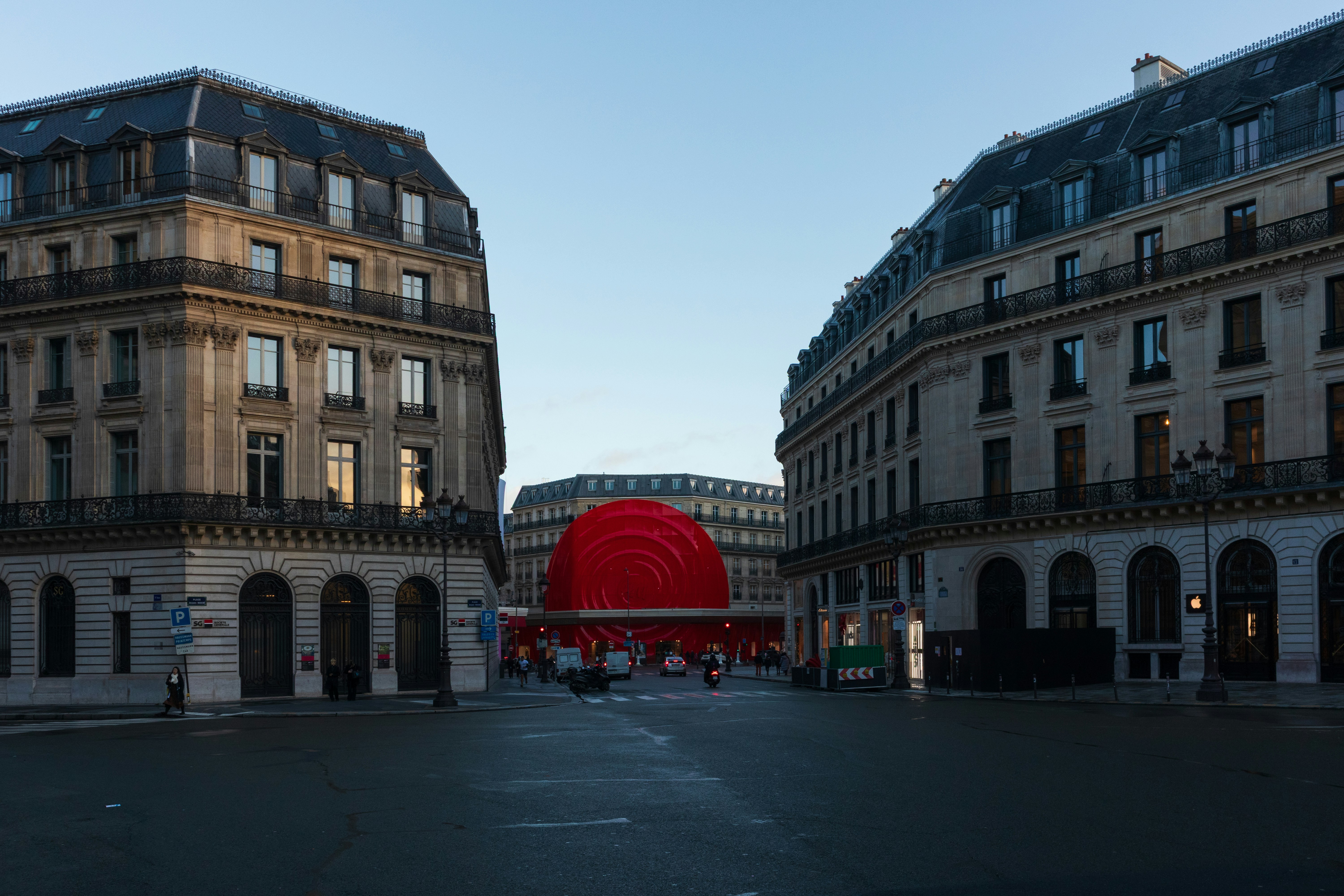 Grande sculpture circulaire rouge entre des immeubles en pierre d'une rue de Paris, à l'image des œuvres exposées en plein air en octobre 2026