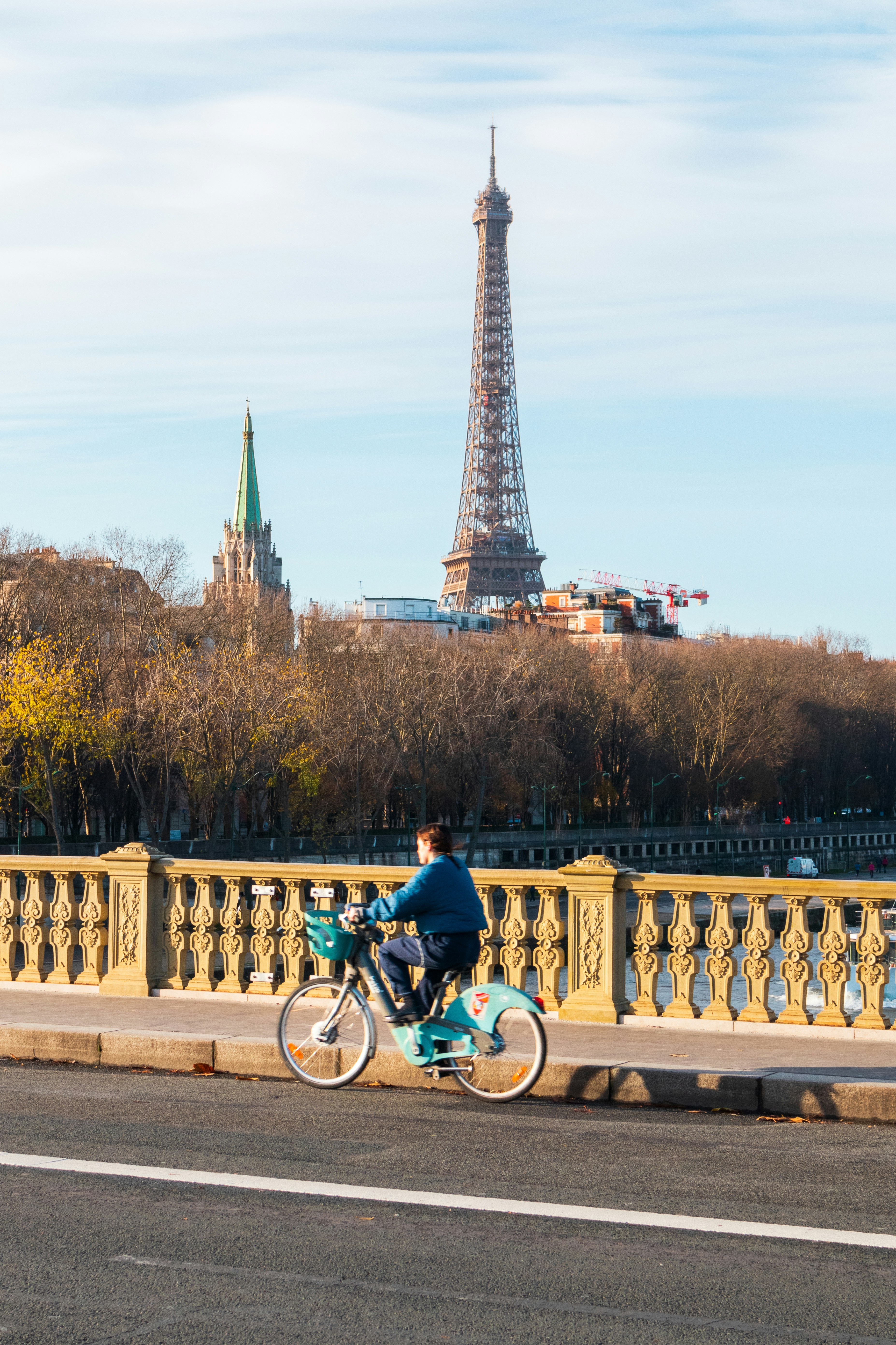 A person cycling on a bridge with the Eiffel Tower in Paris