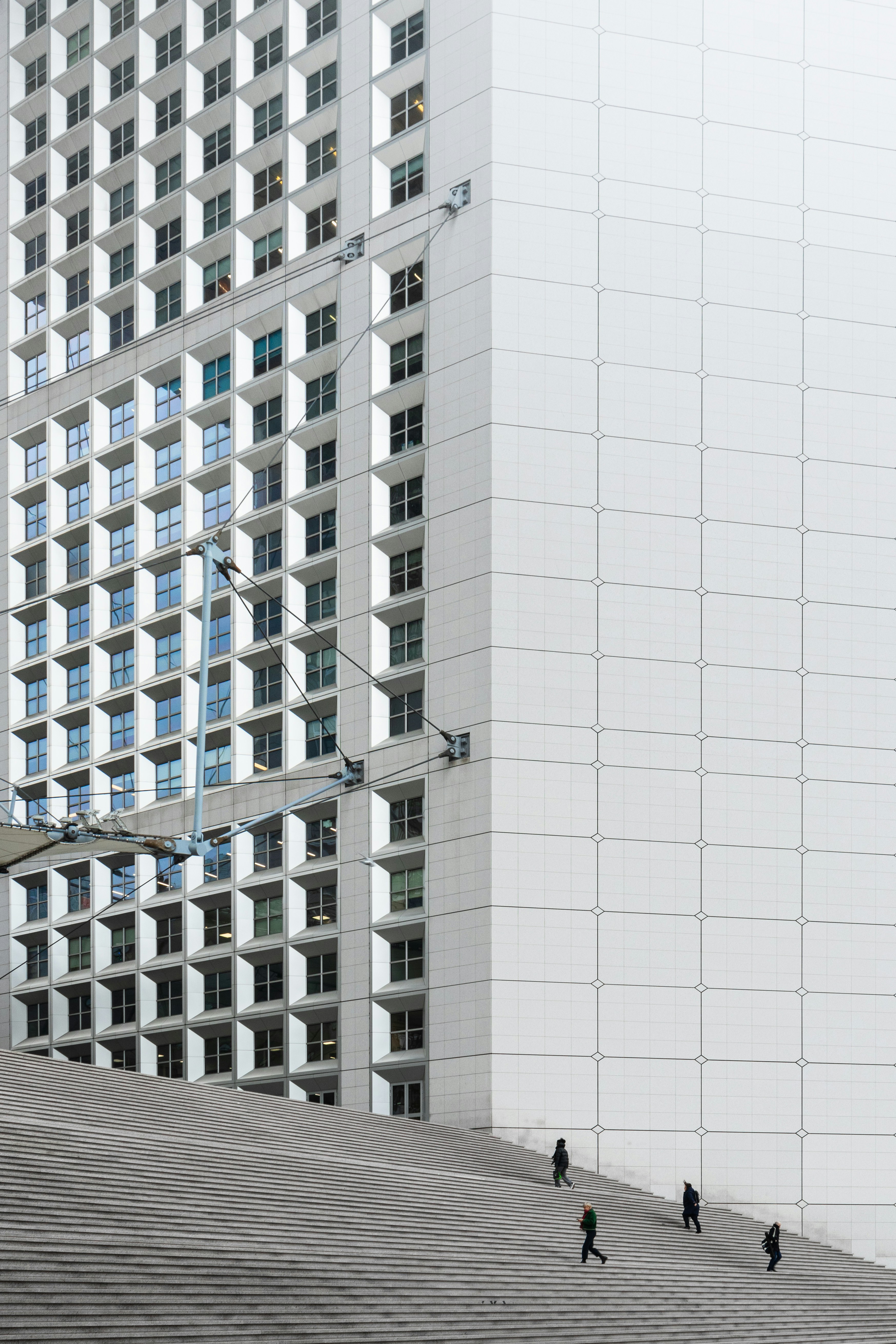 People walking up the wide stone steps of the Grande Arche in Paris