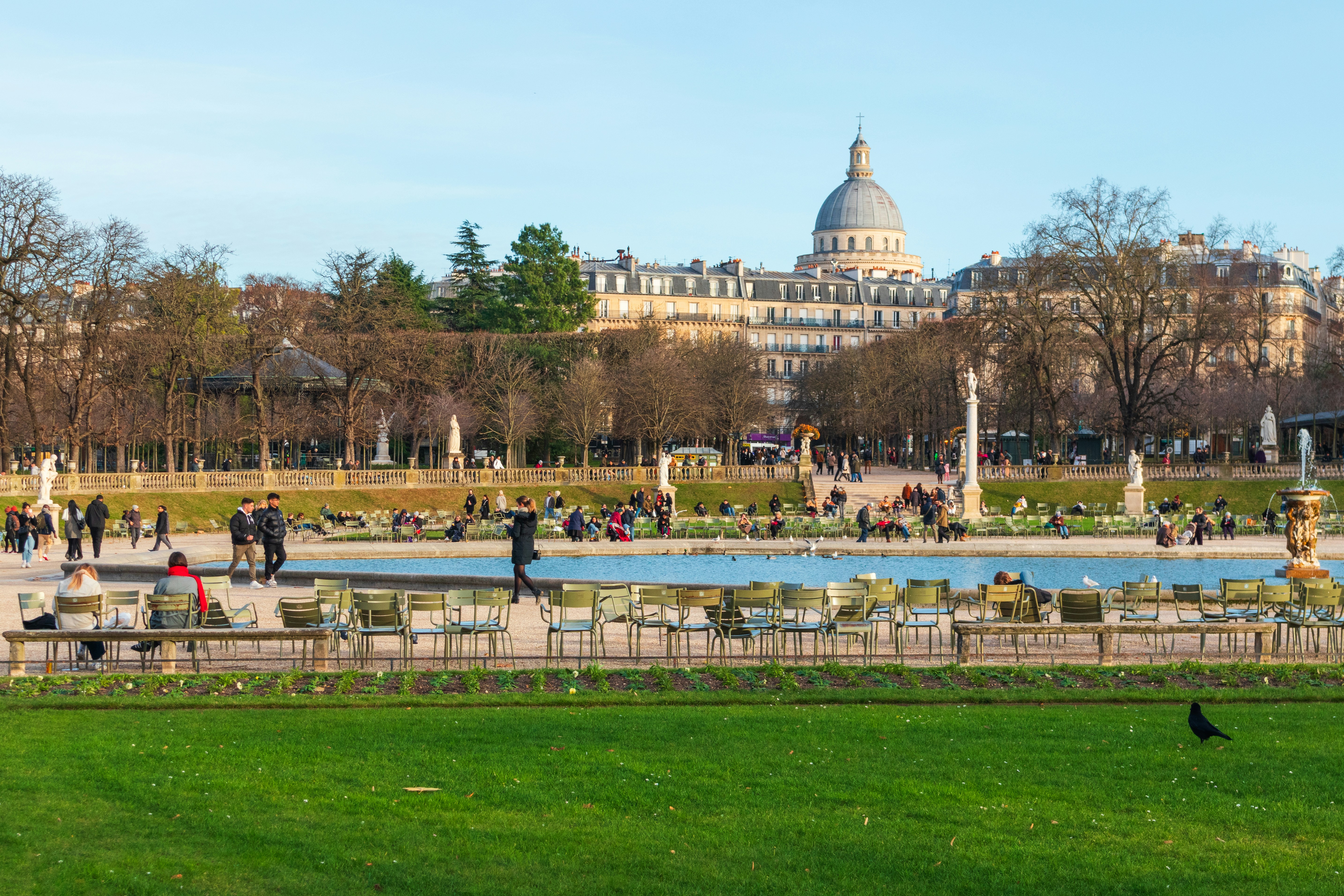 People relaxing on green chairs by a pond in the Luxembourg Gardens in Paris
