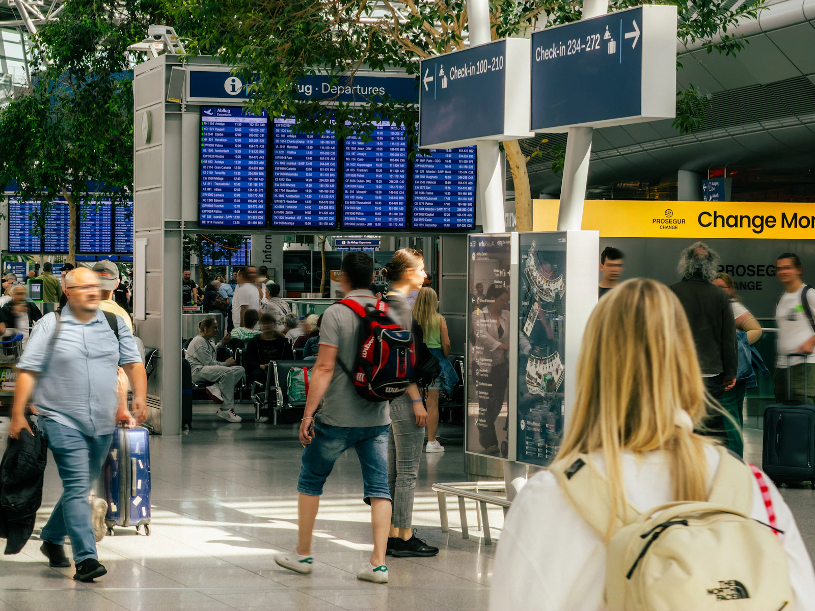 Travelers walking past flight departure boards in an airport terminal