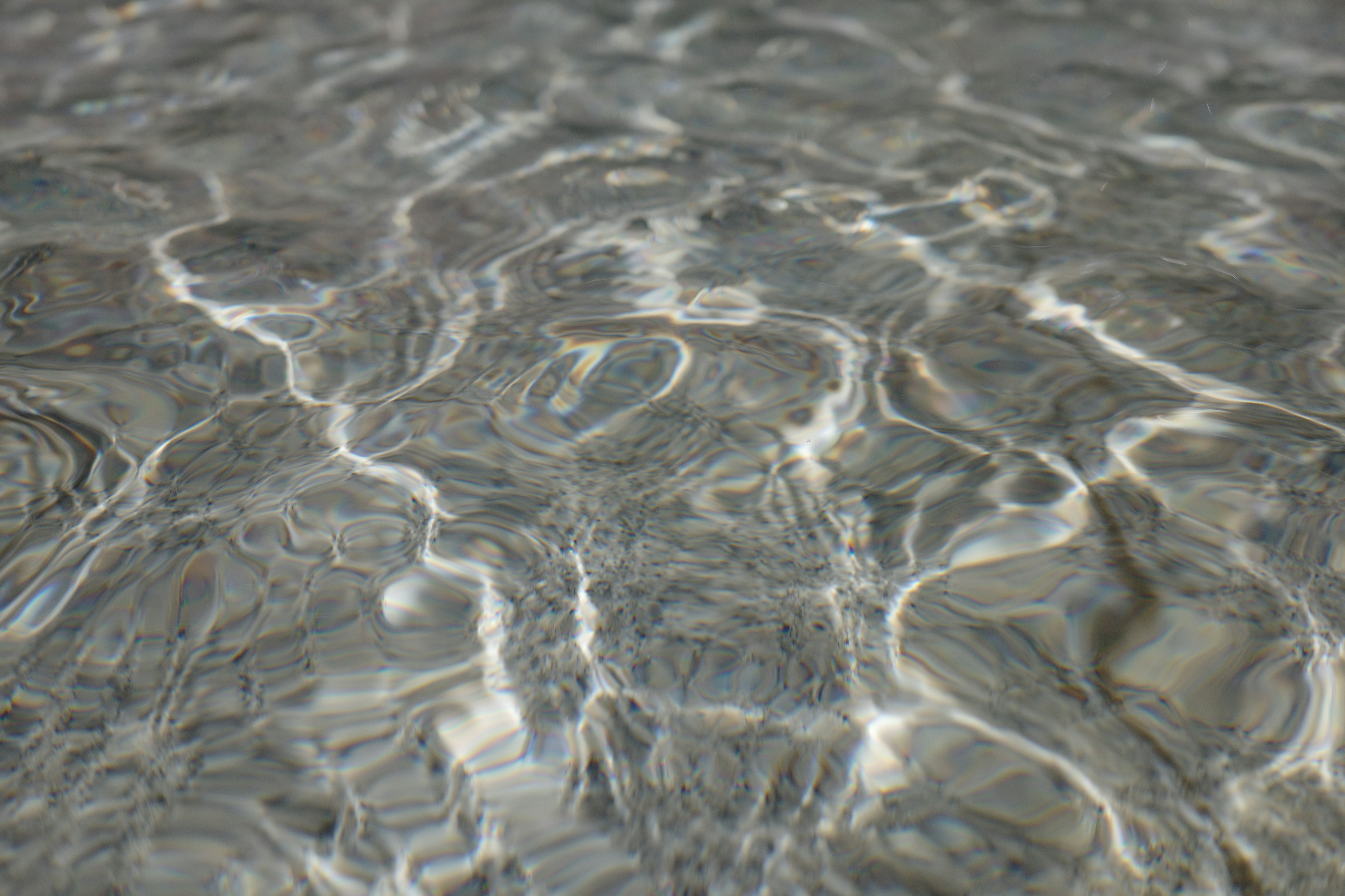 Clear water with ripples and bright light reflections on a sandy bottom
